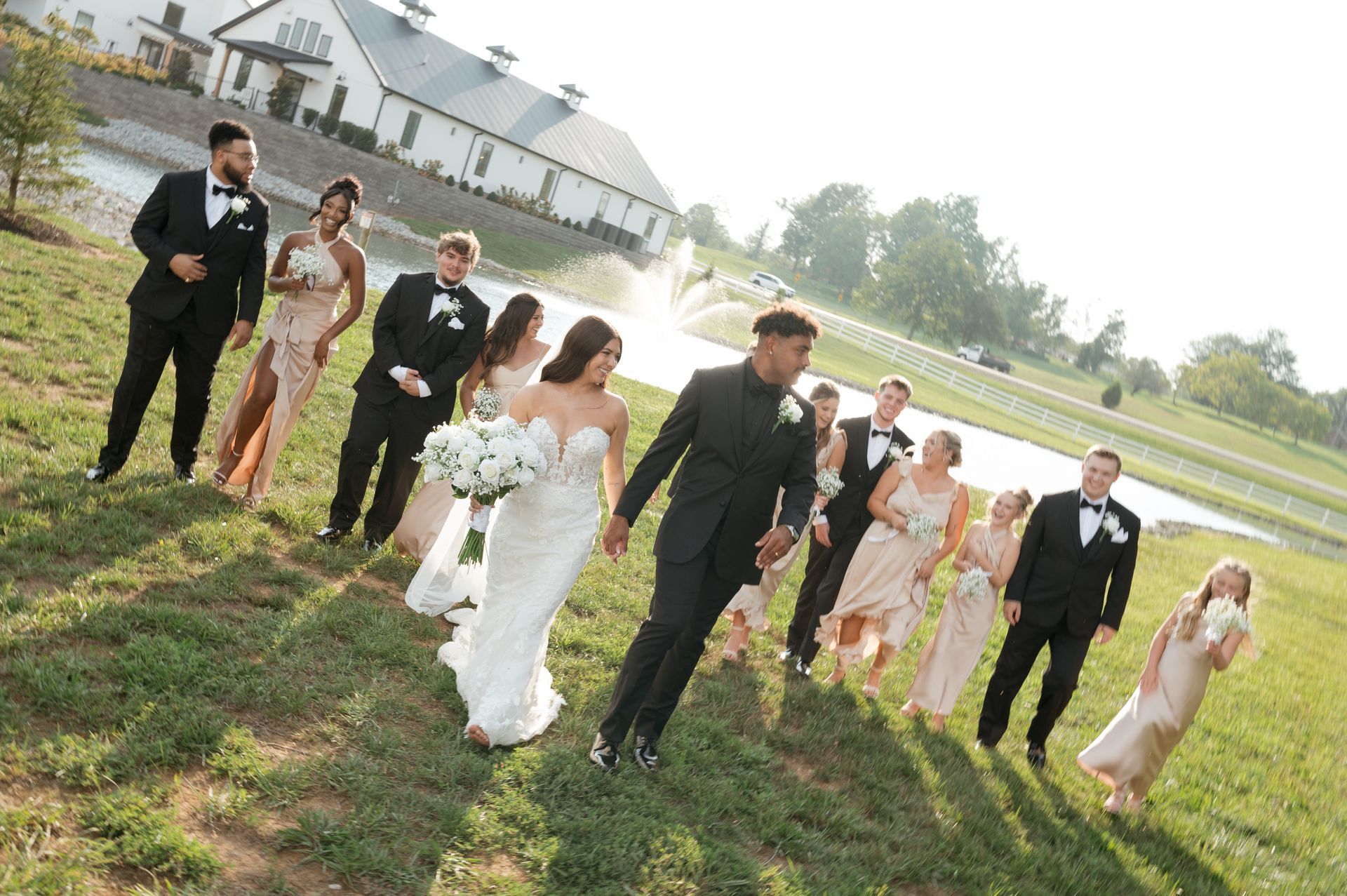 A bride and groom are walking with their wedding party in a field.