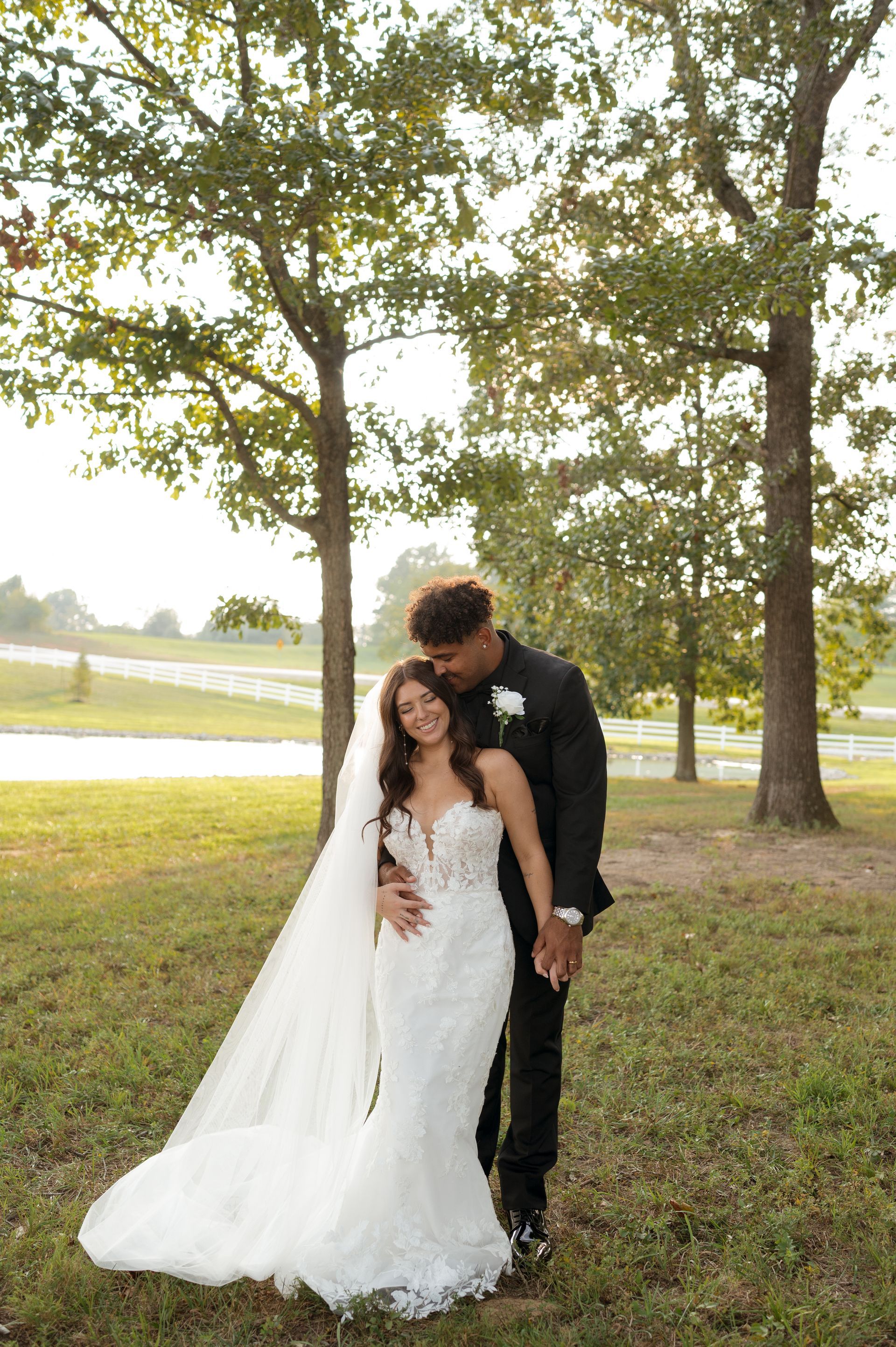 A bride and groom are posing for a picture in a field.