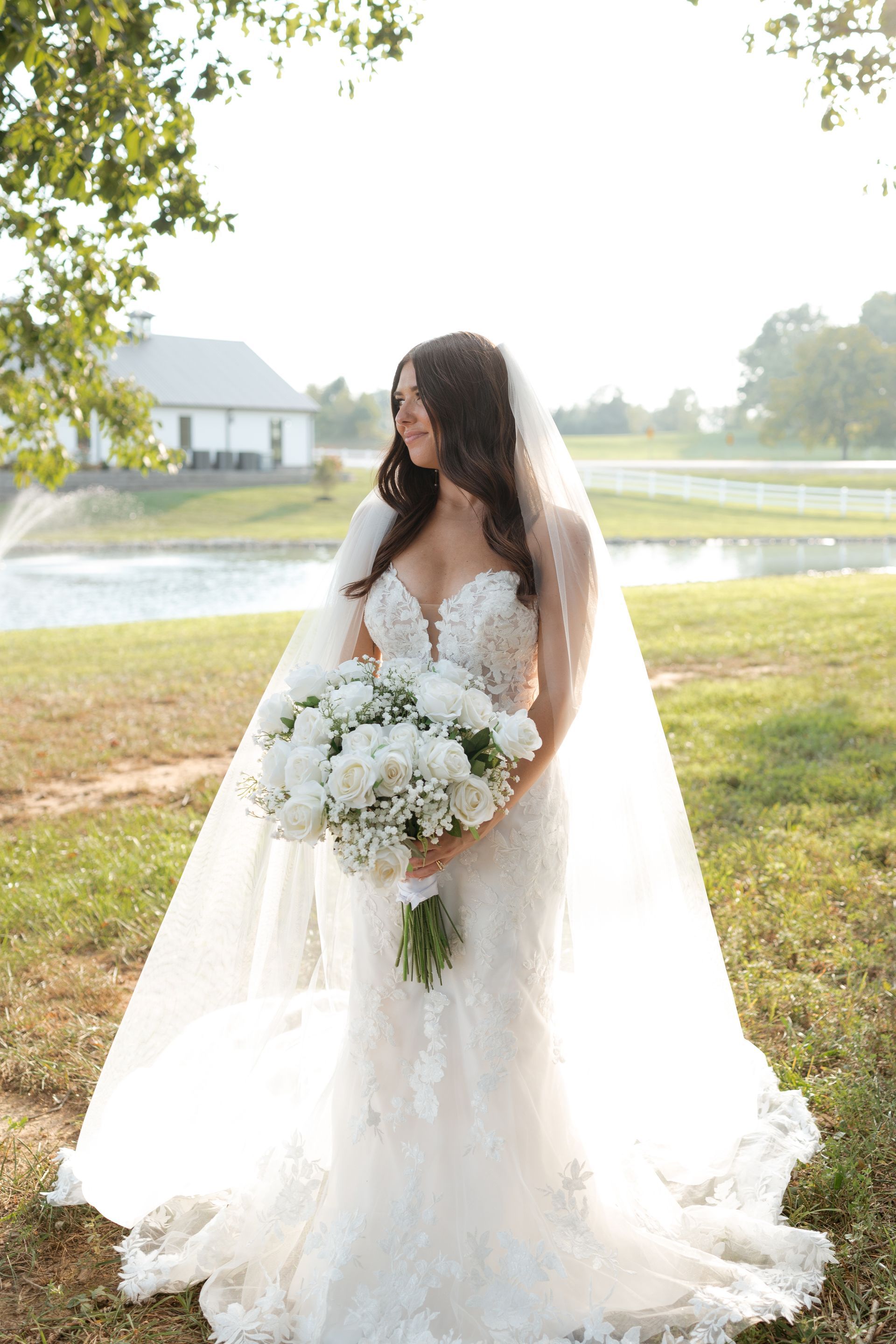 A bride in a wedding dress and veil is holding a bouquet of white flowers.