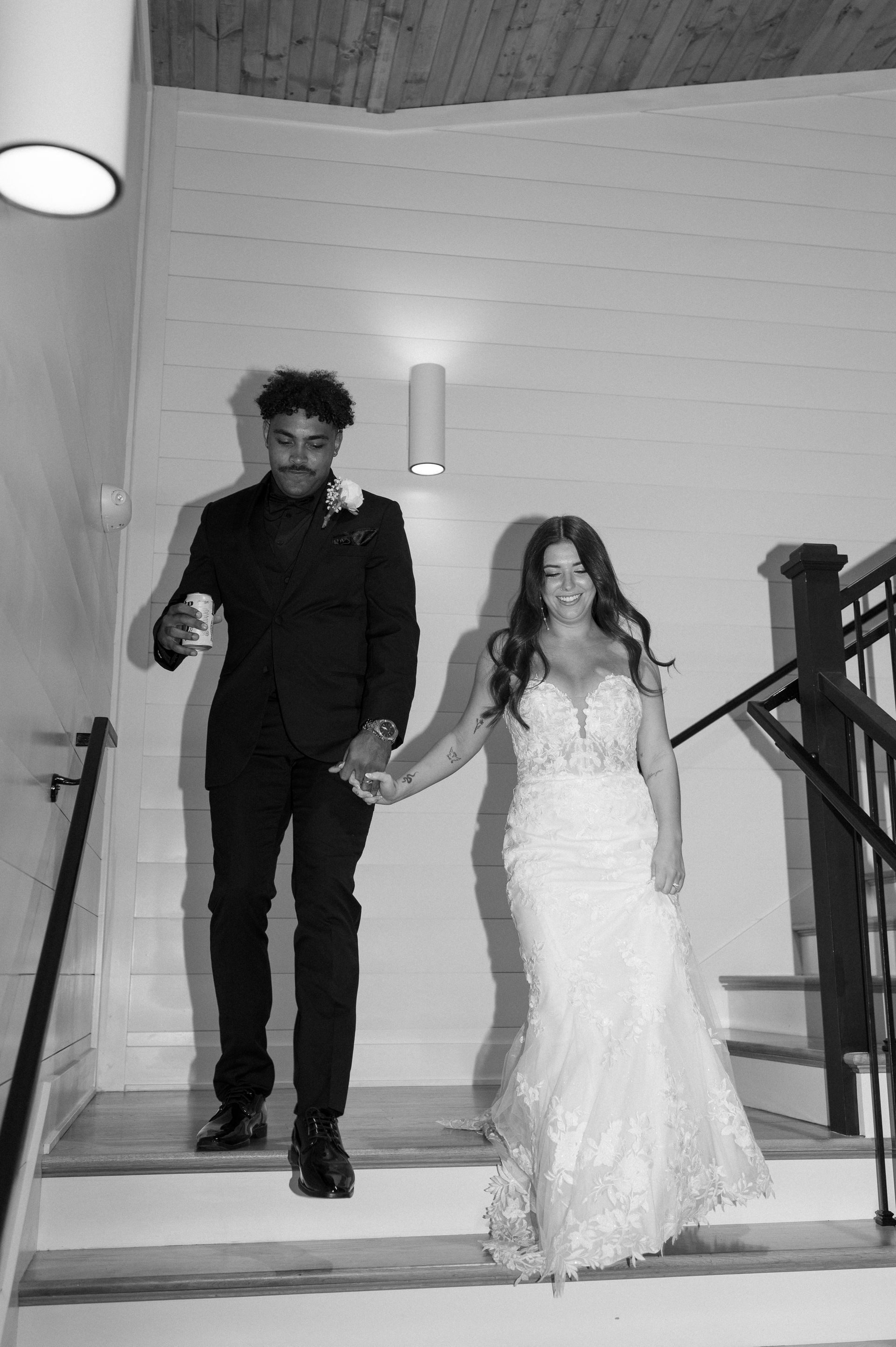 A bride and groom are walking down the stairs holding hands.