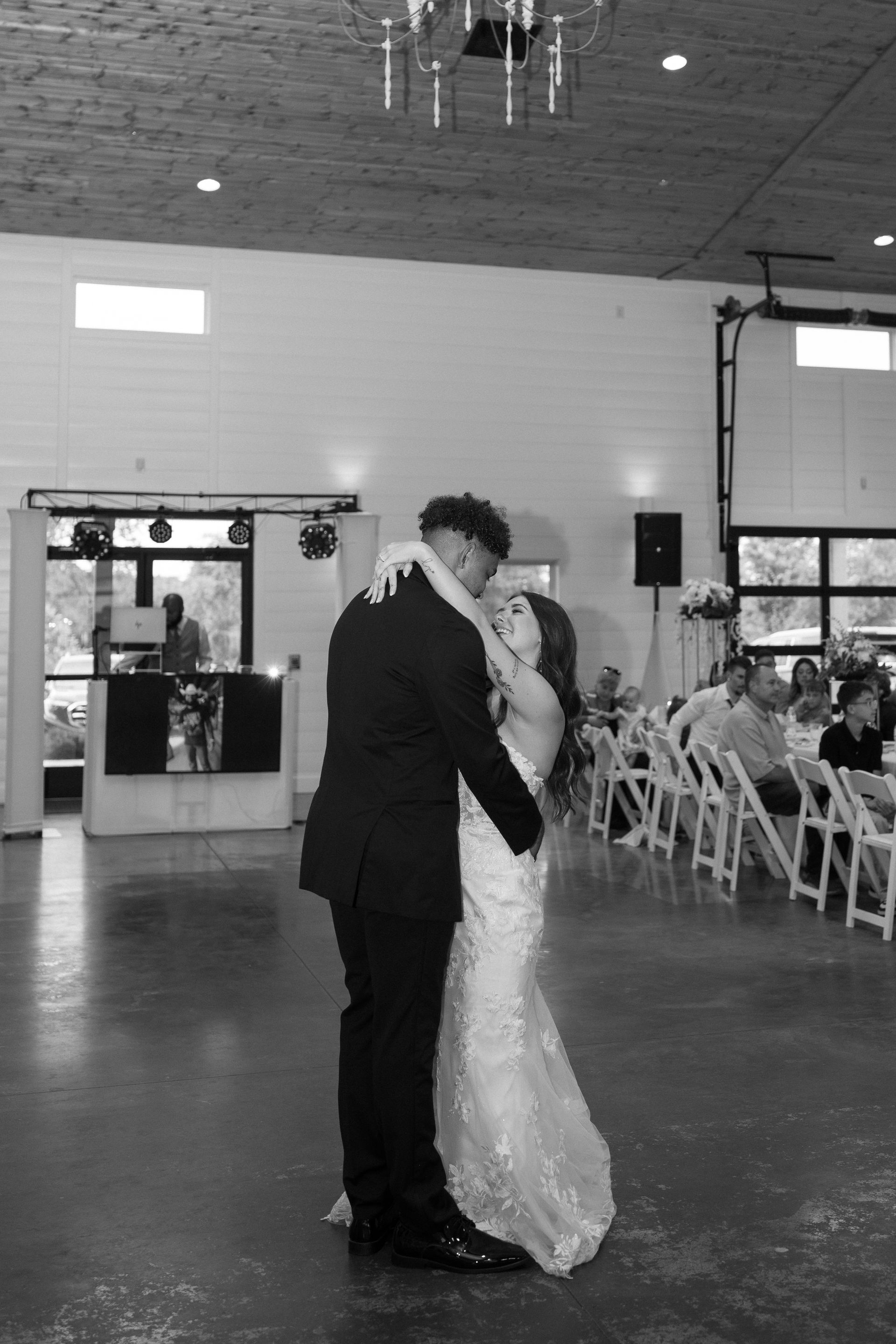 A black and white photo of a bride and groom dancing at their wedding reception.