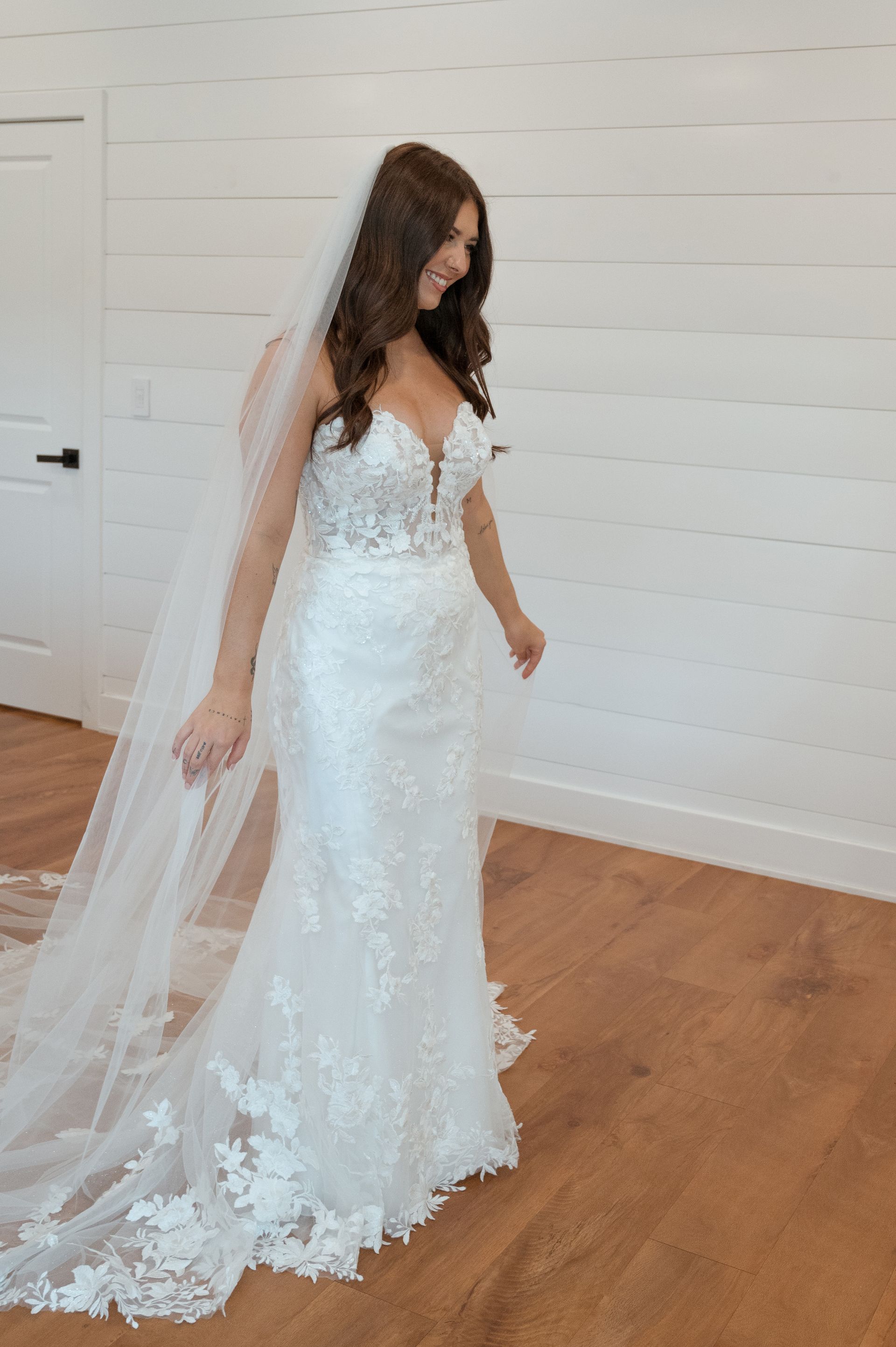 A woman in a wedding dress and veil is standing in a room.
