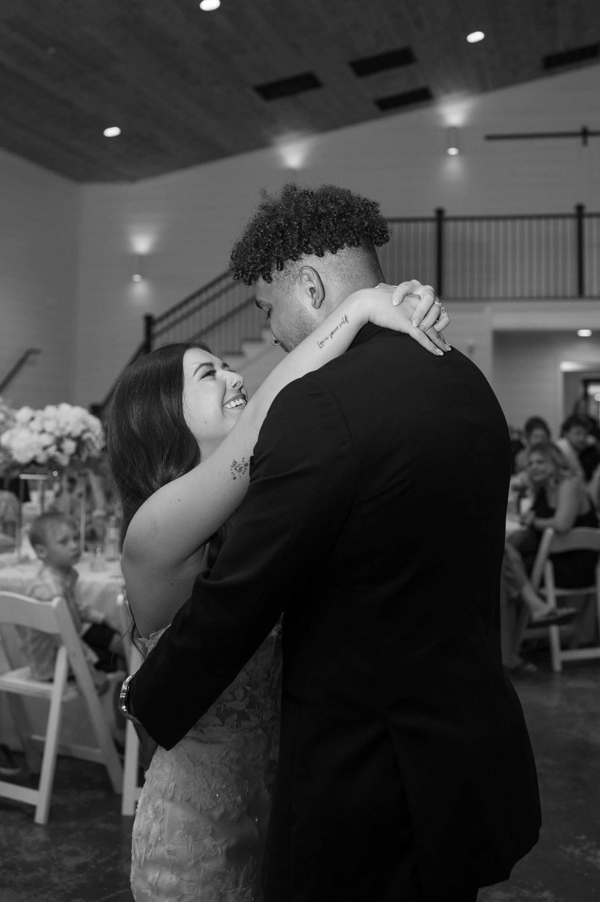 A black and white photo of a bride and groom dancing at their wedding reception.