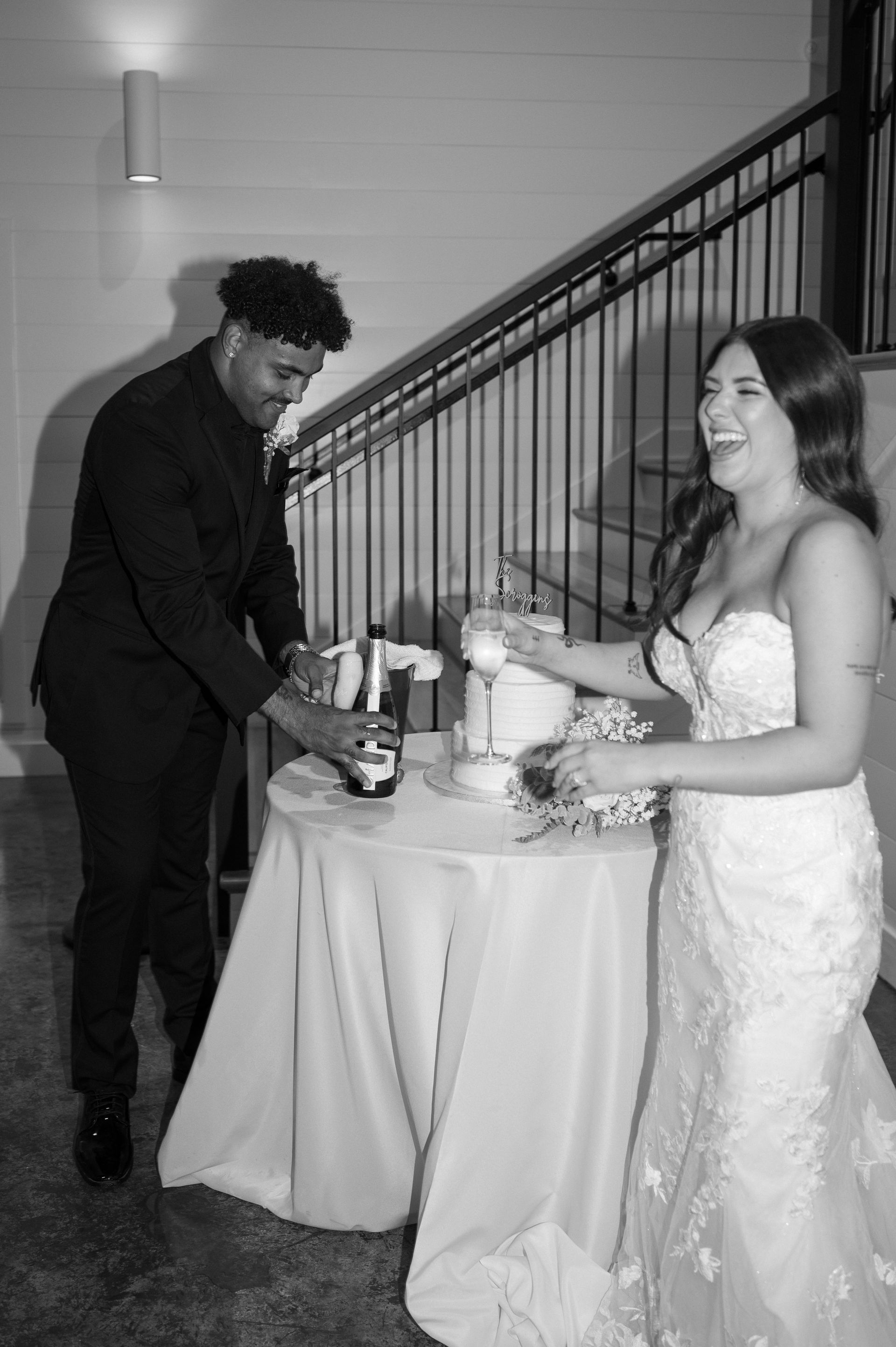 A black and white photo of a bride and groom cutting their wedding cake.