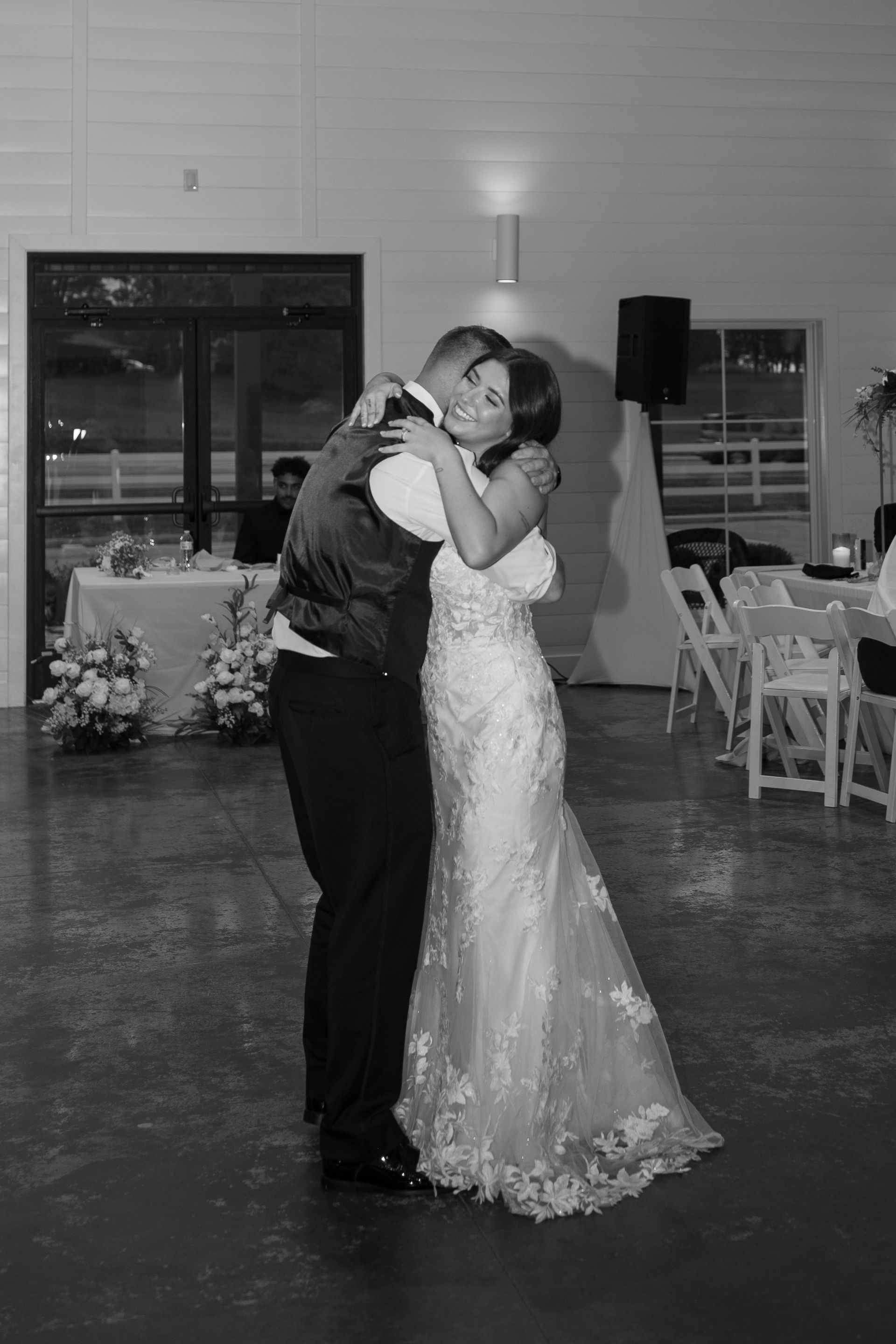 A bride and groom are hugging each other while dancing at their wedding reception.
