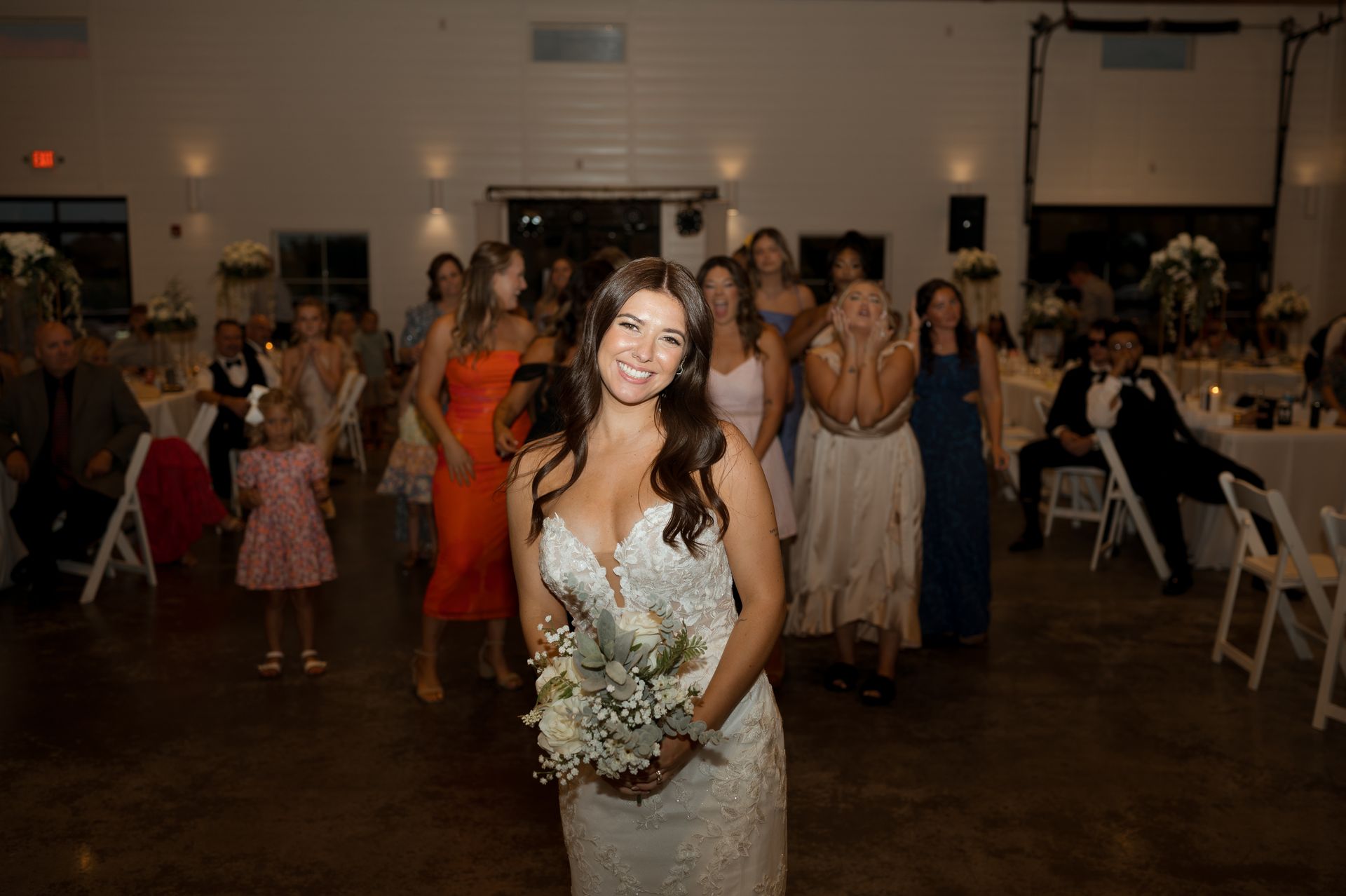 A bride is throwing a bouquet of flowers at her wedding reception.