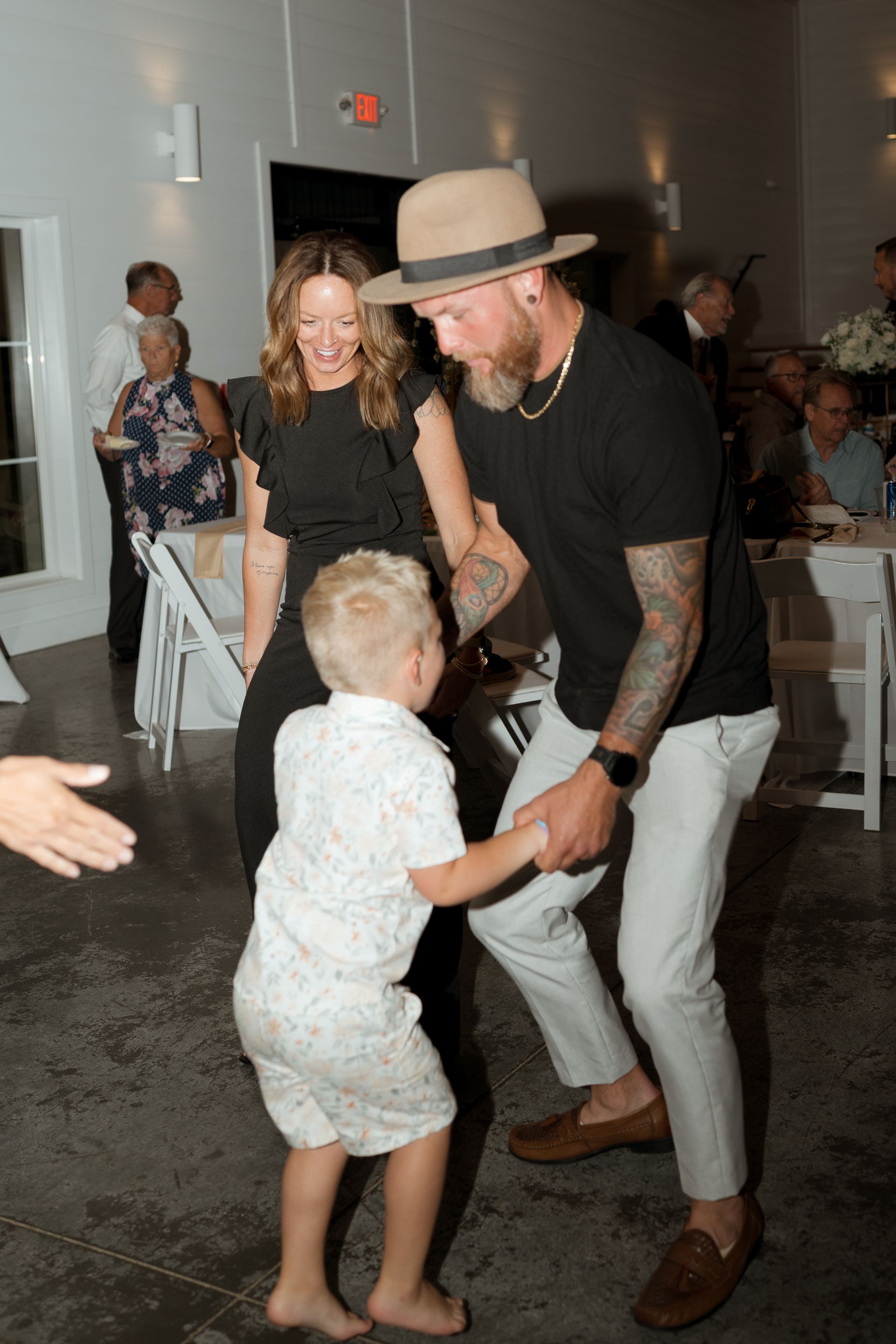 A man and woman are dancing with a little boy at a wedding reception.