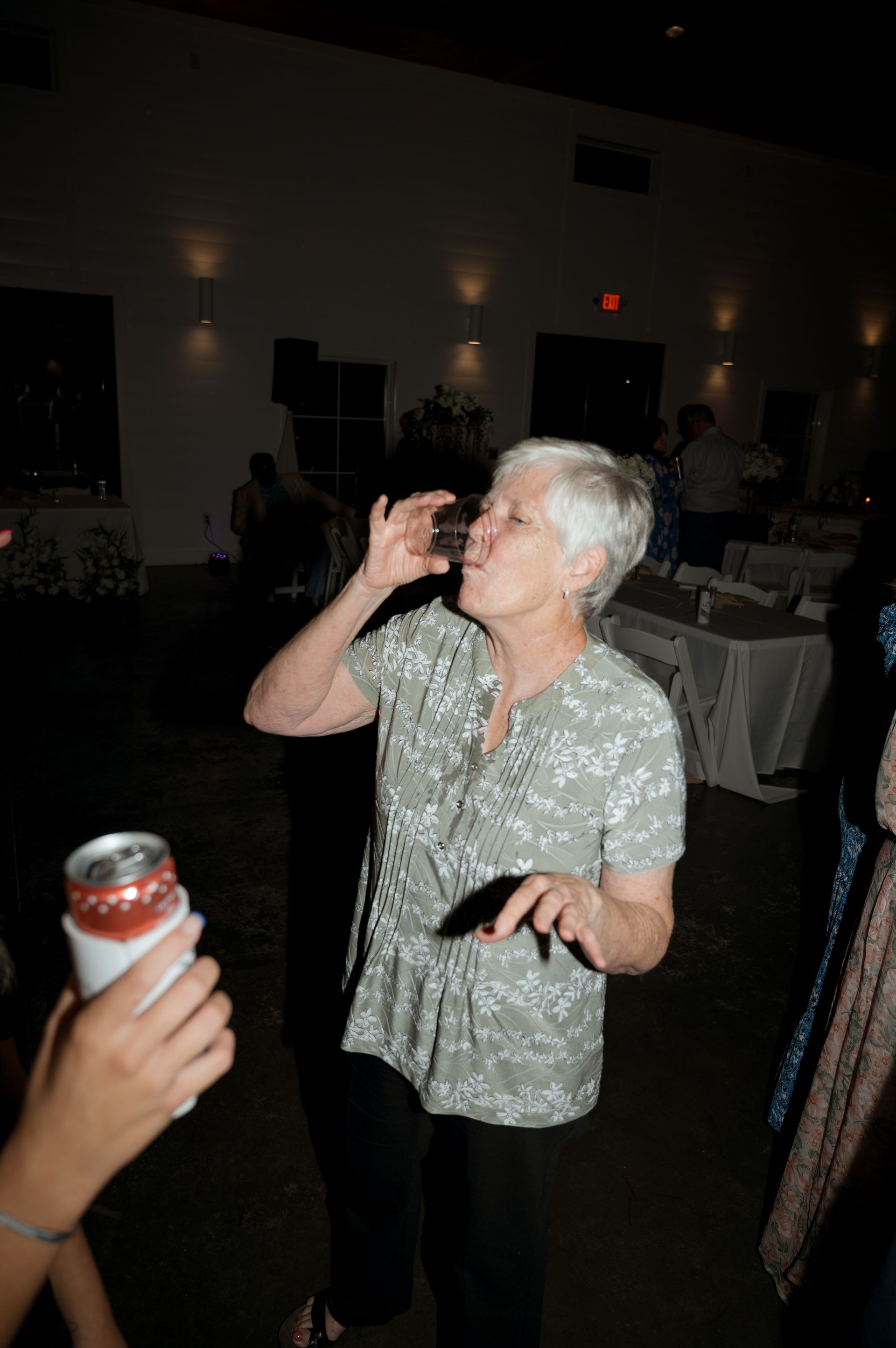 A woman is drinking from a can while dancing at a party
