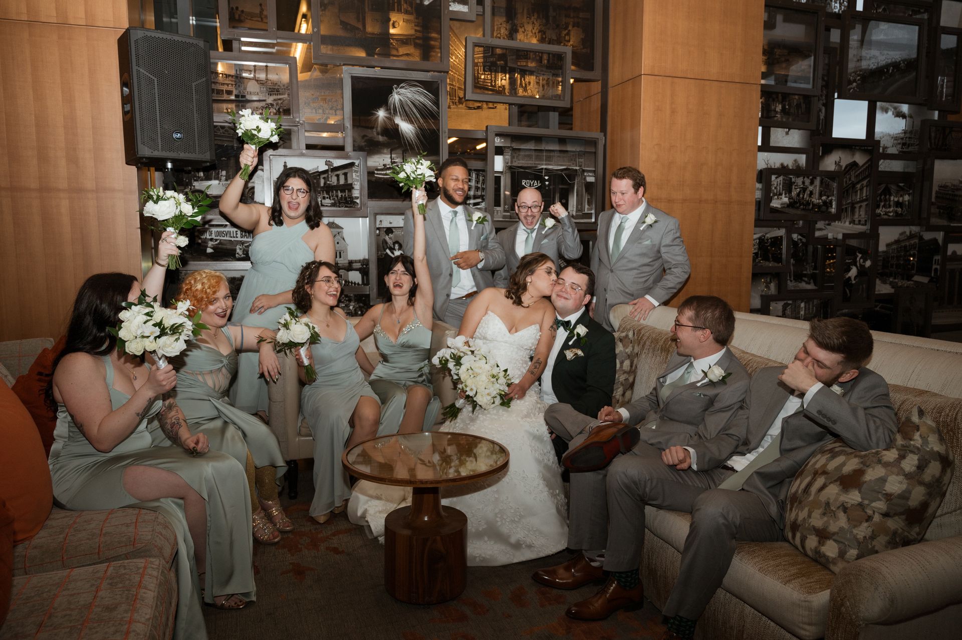 A bride and groom are sitting on a couch with their wedding party.