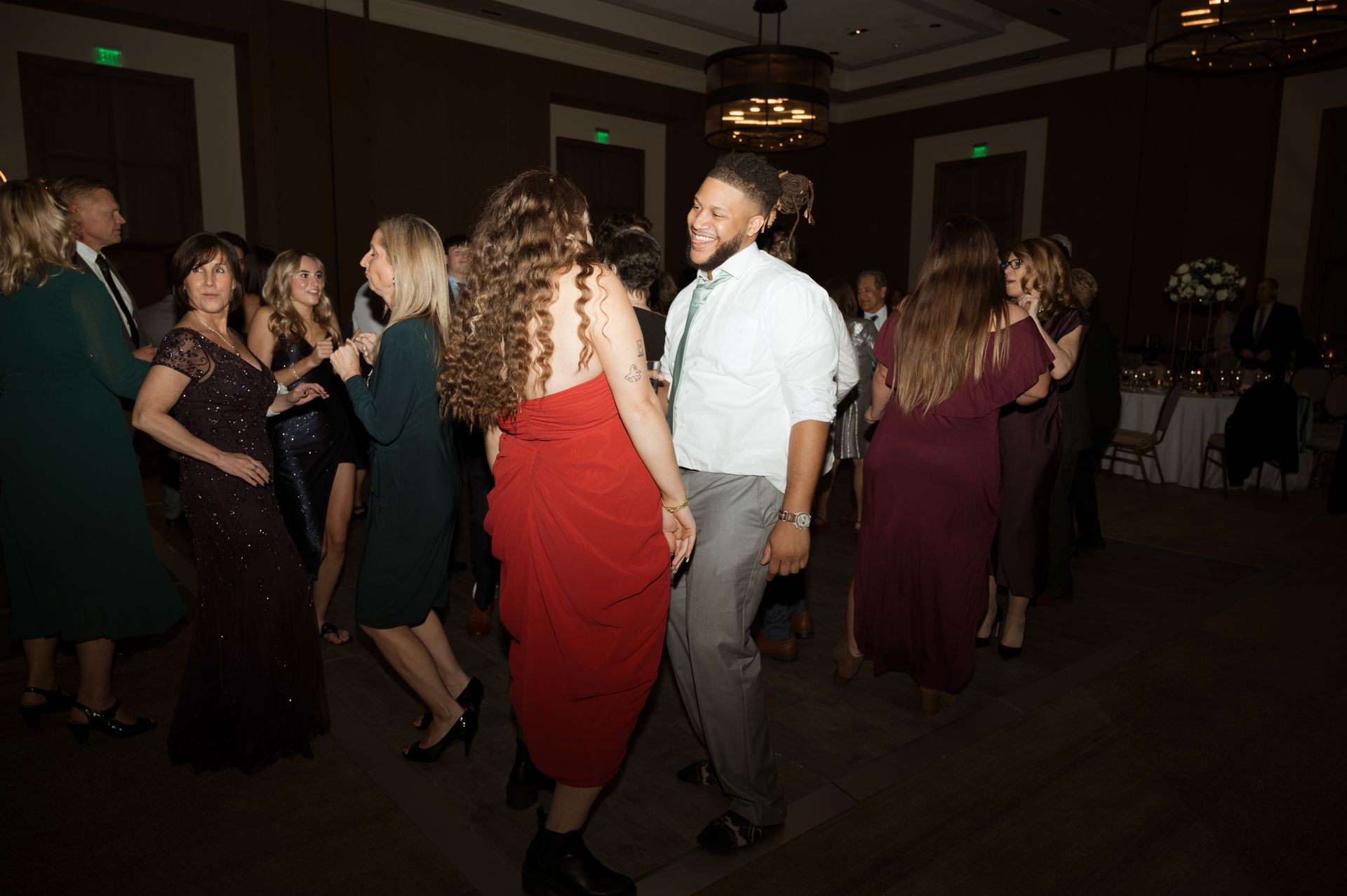 A group of people are dancing in a room at a wedding reception.