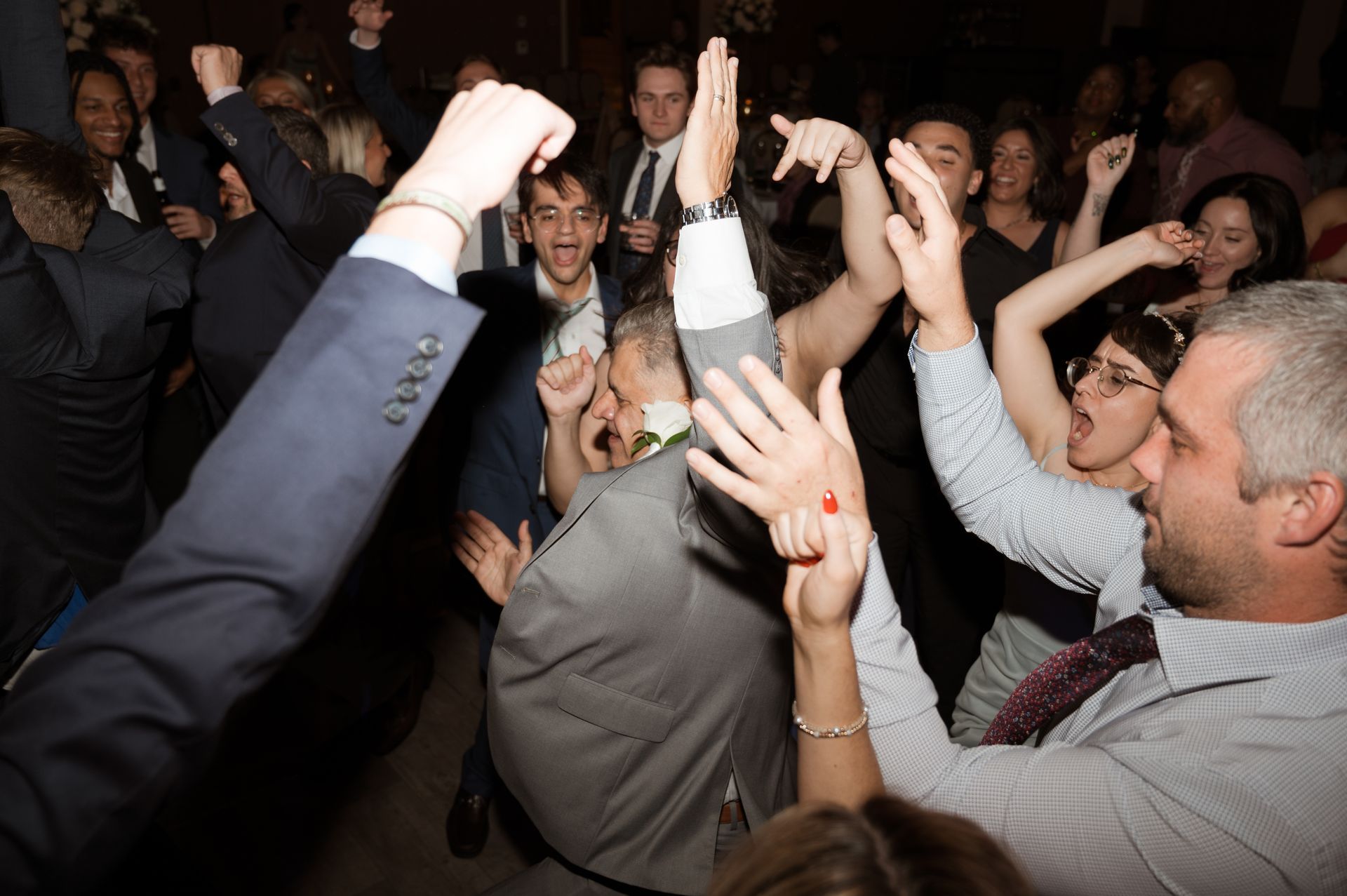 A crowd of people are dancing with their hands in the air