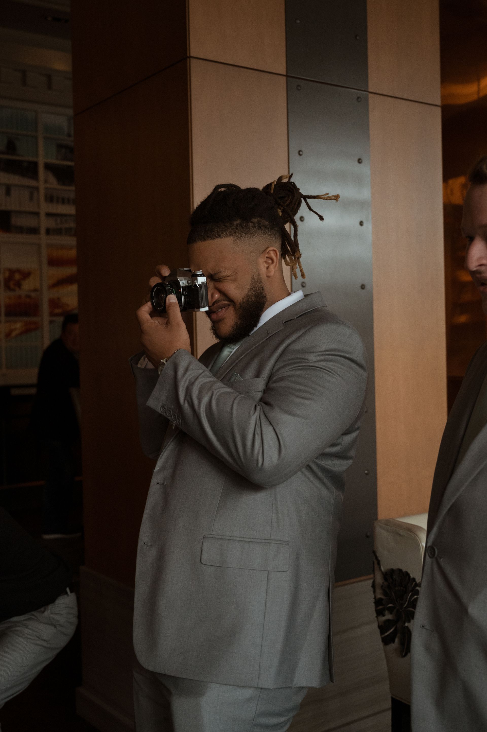 A man in a suit is taking a picture with a camera.