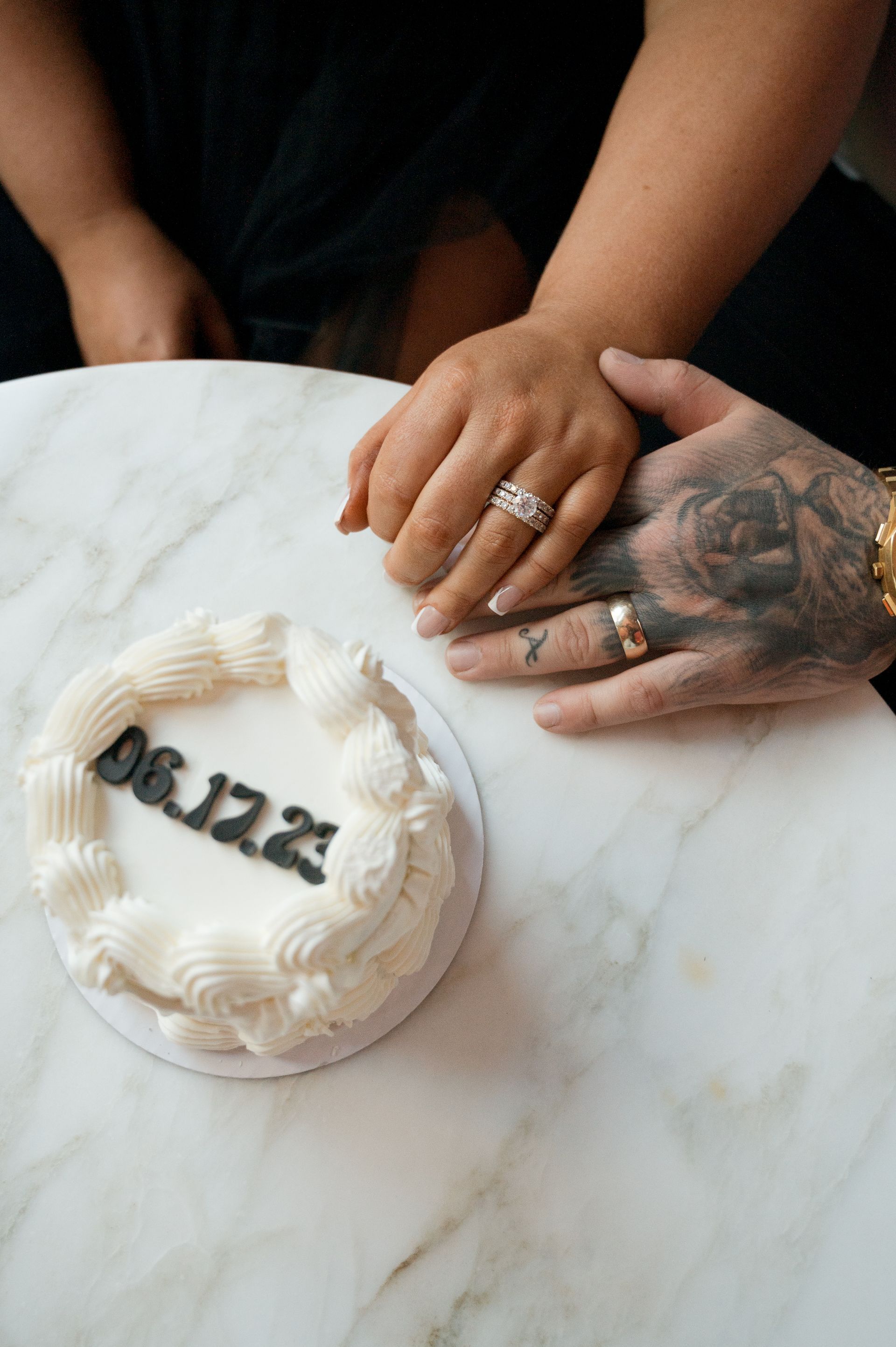A man and a woman are holding hands next to a cake that says 06.12.21