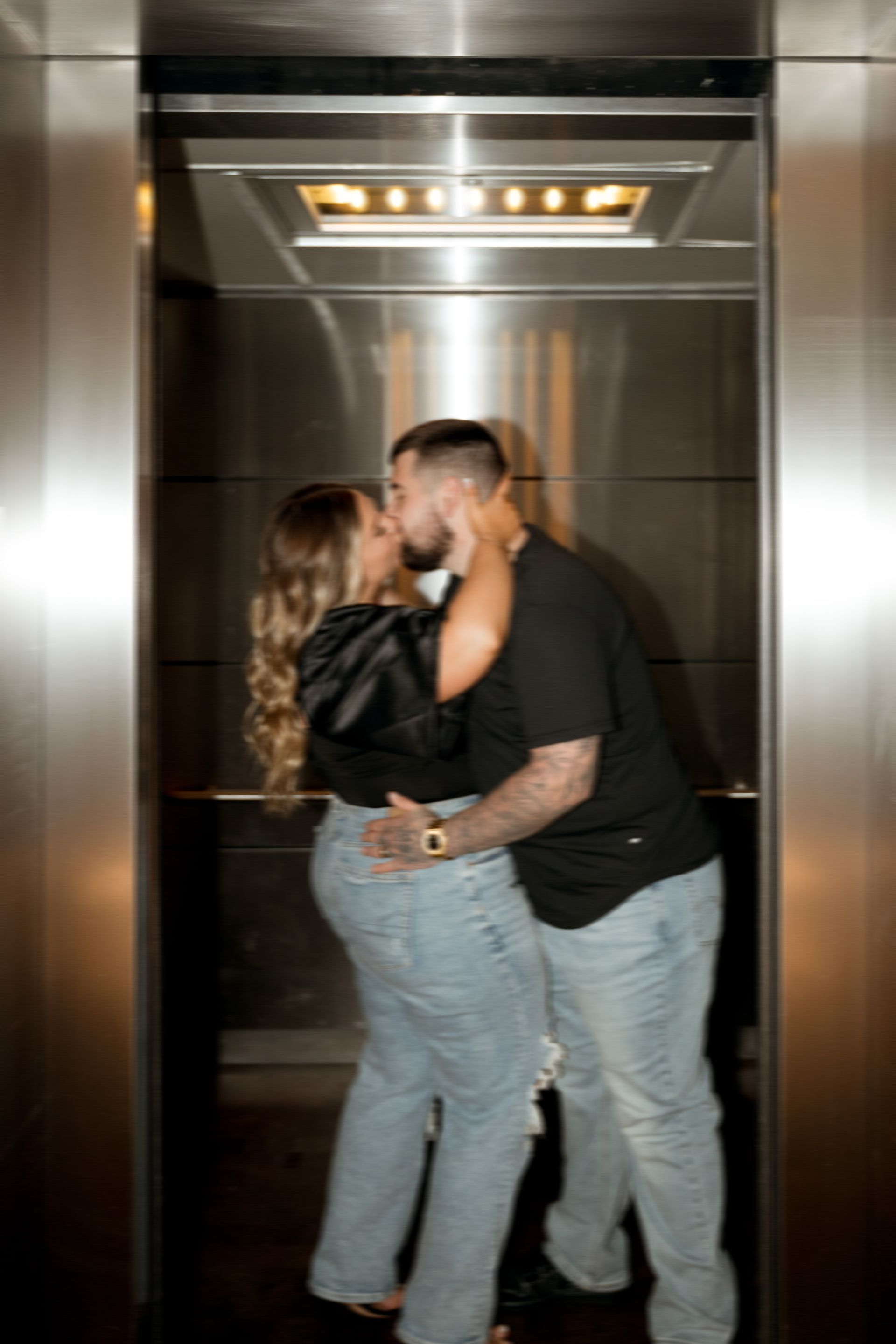 A man and a woman are kissing in an elevator.