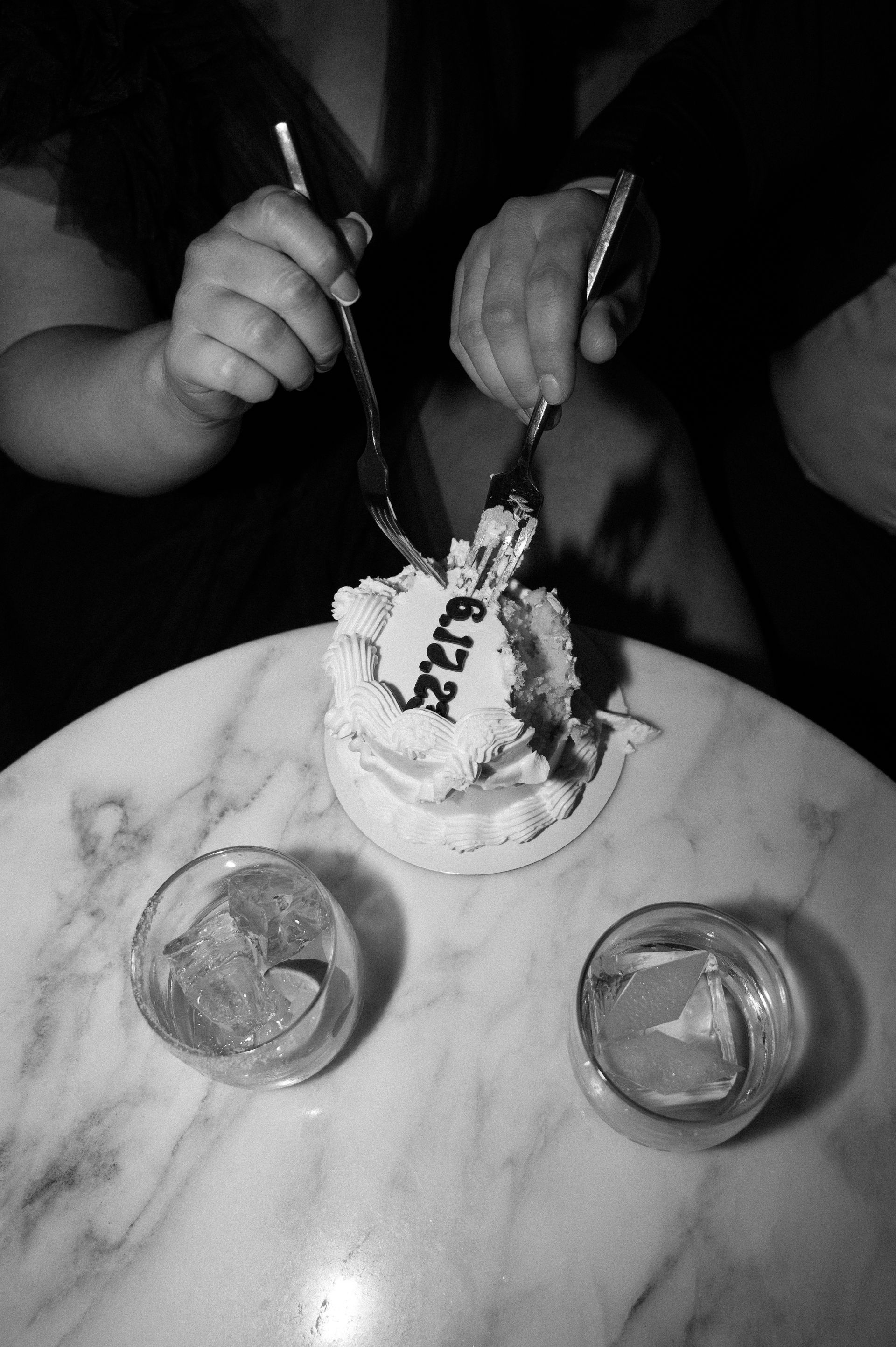 A black and white photo of a person cutting a cake