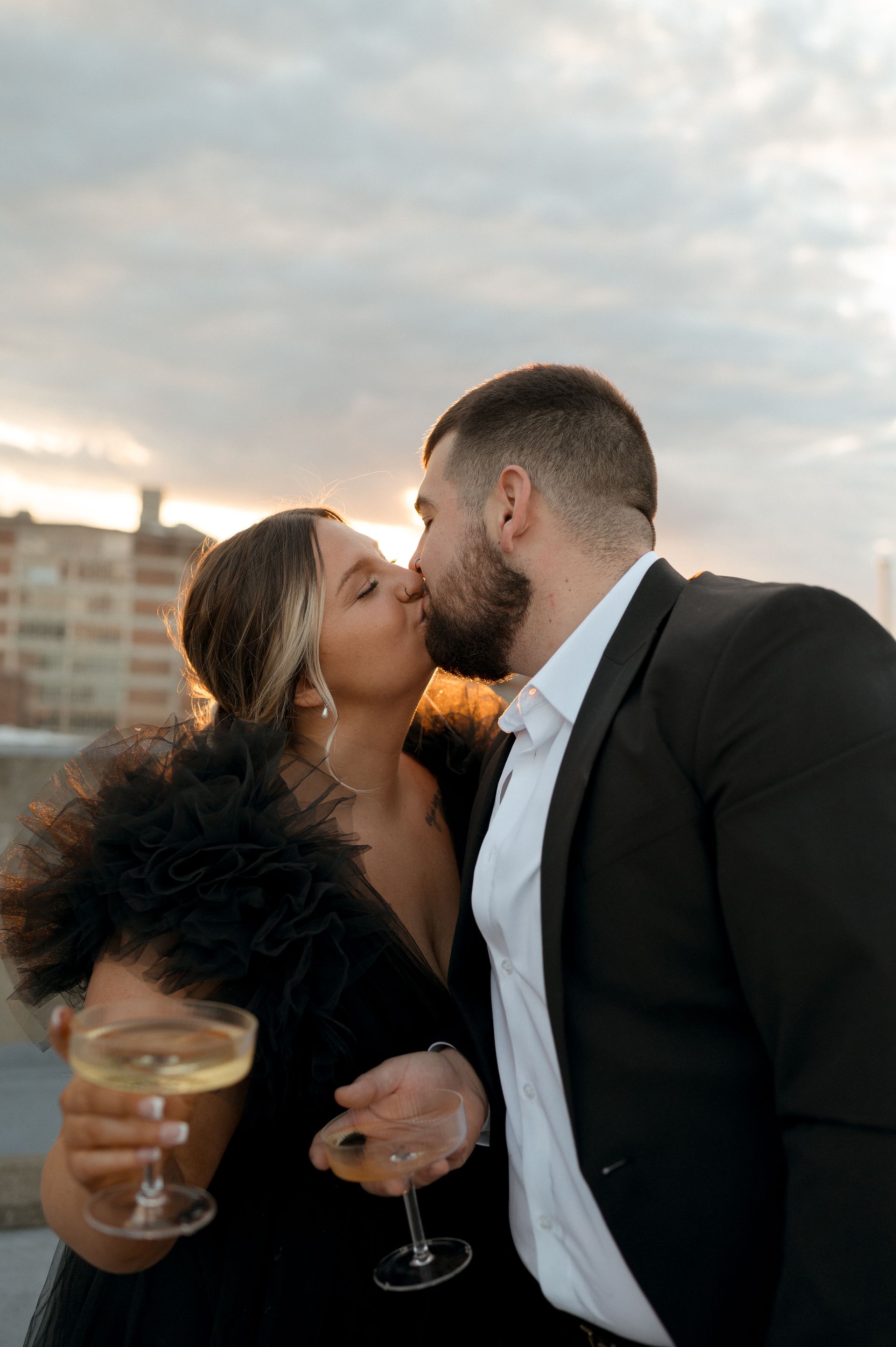 A man and a woman are kissing while holding champagne glasses.