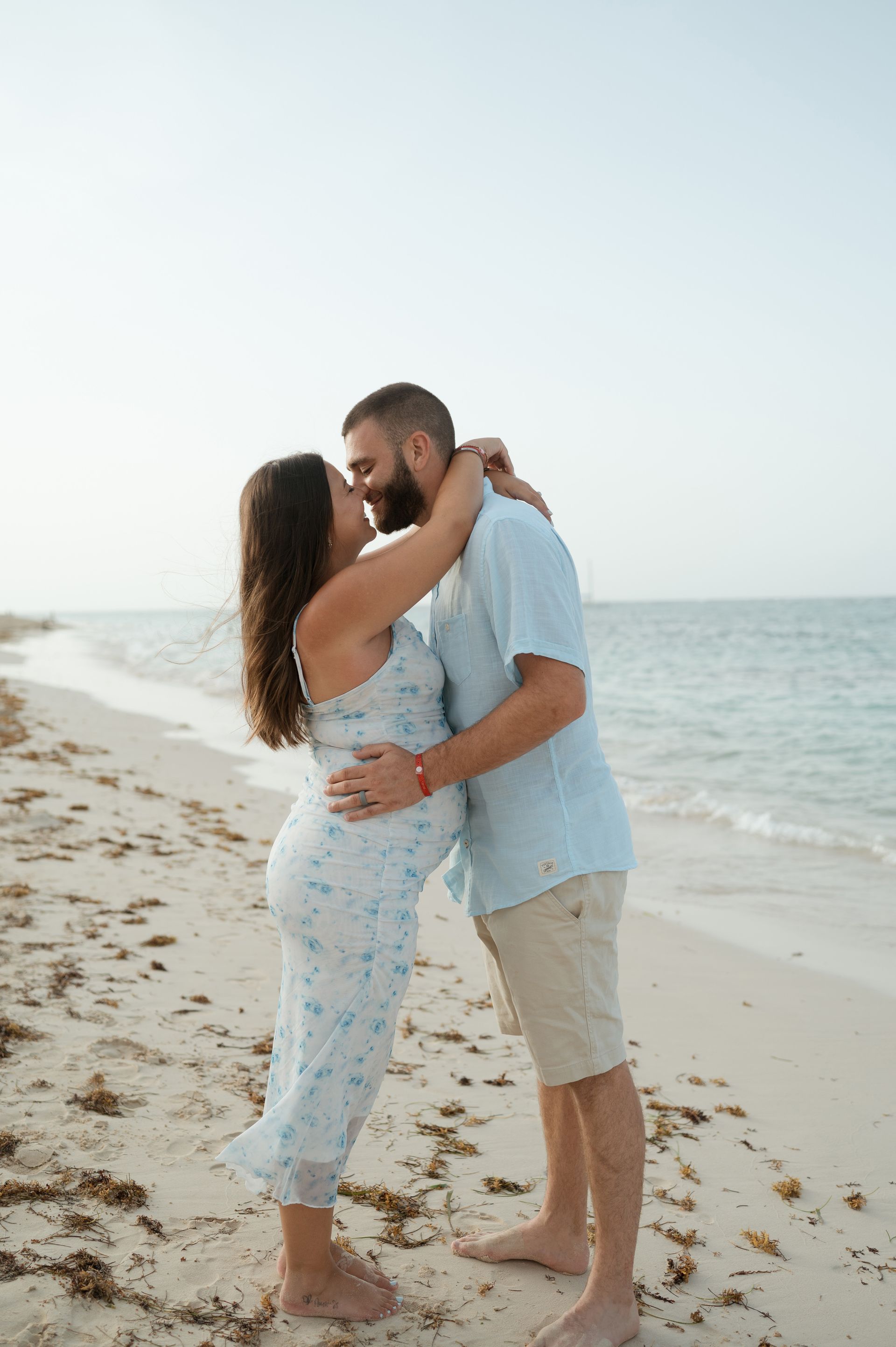 A man and a woman are kissing on the beach.