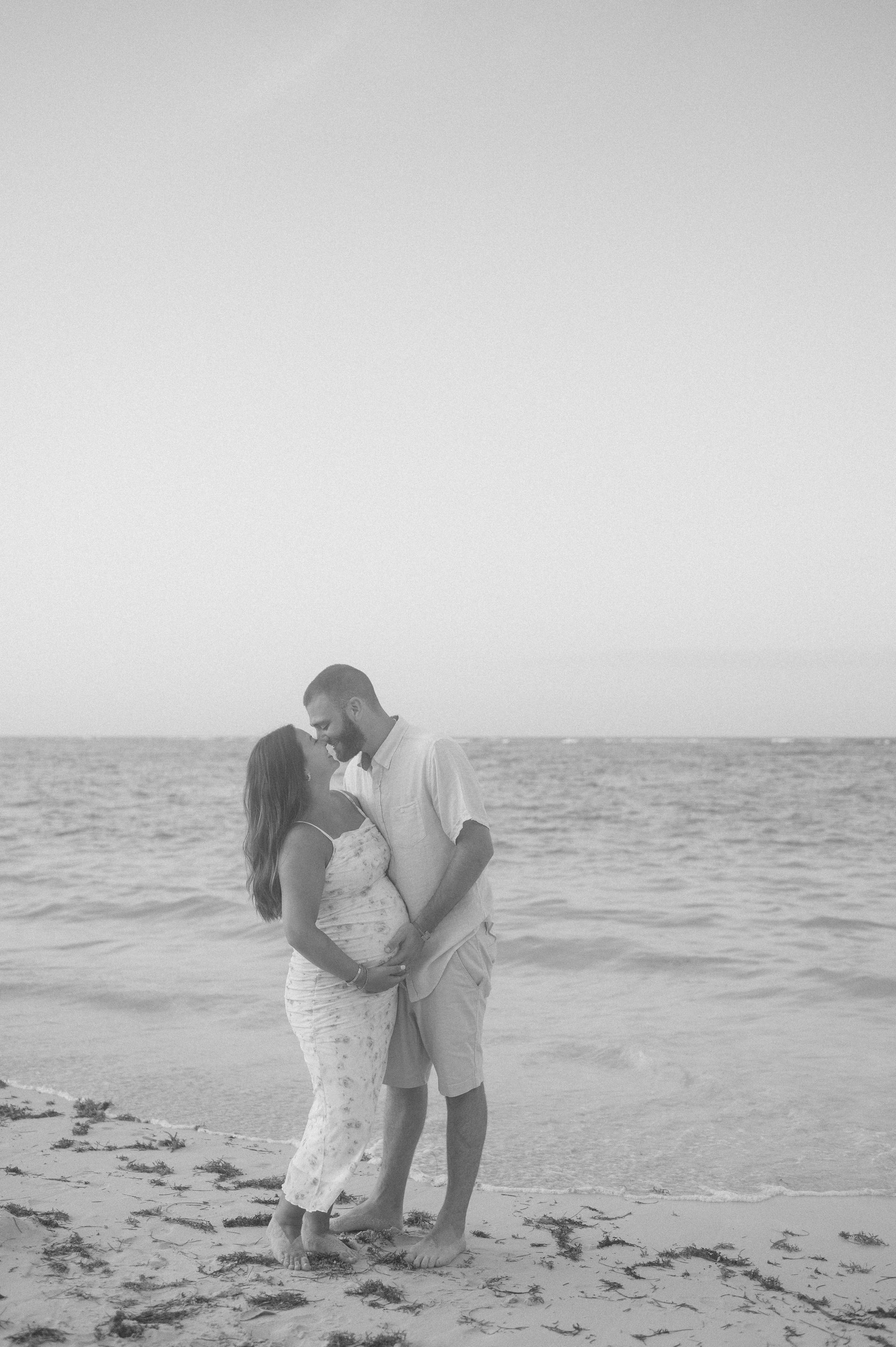 A man and a woman are kissing on the beach.