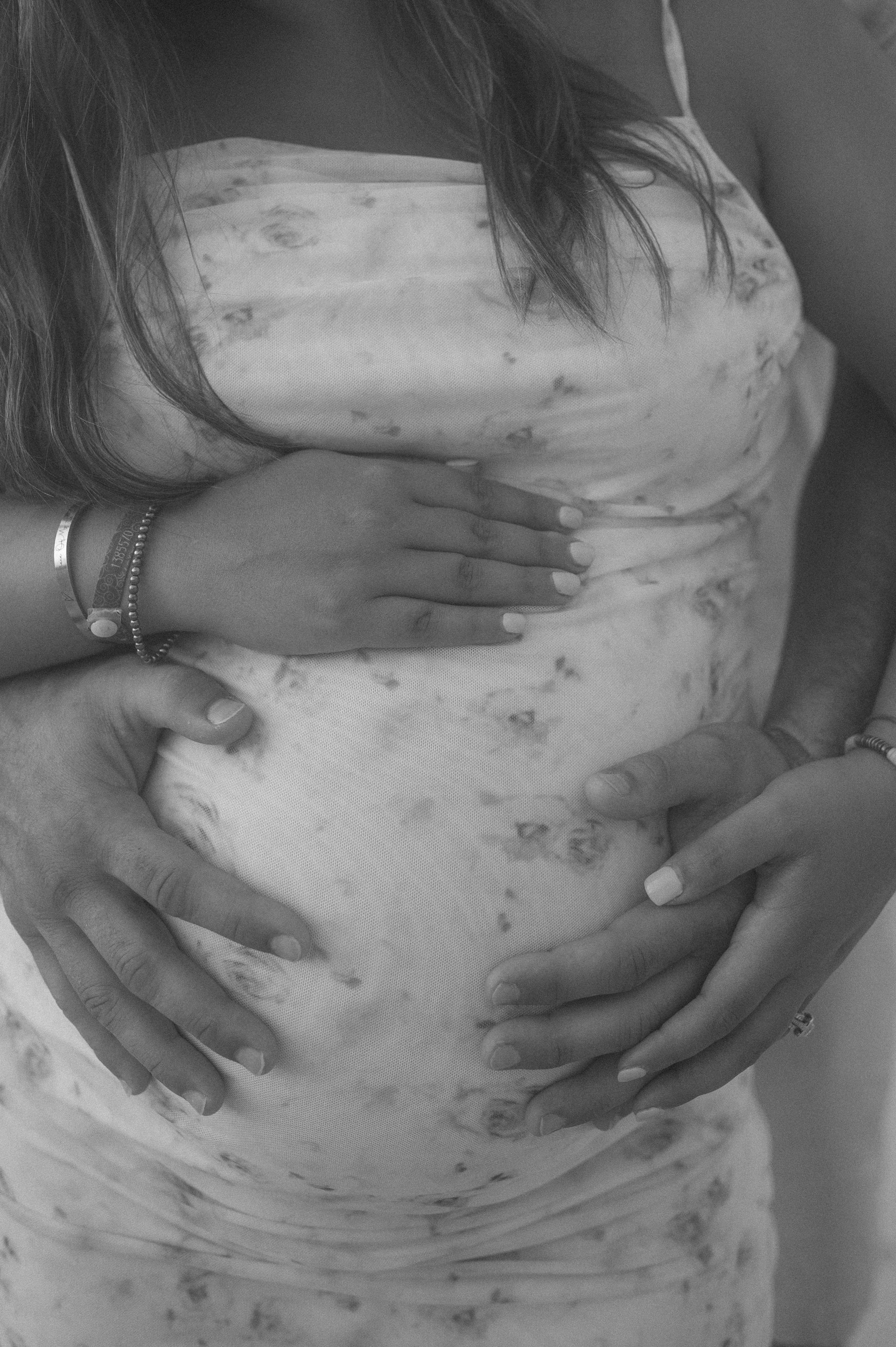 A black and white photo of a pregnant woman holding her belly.