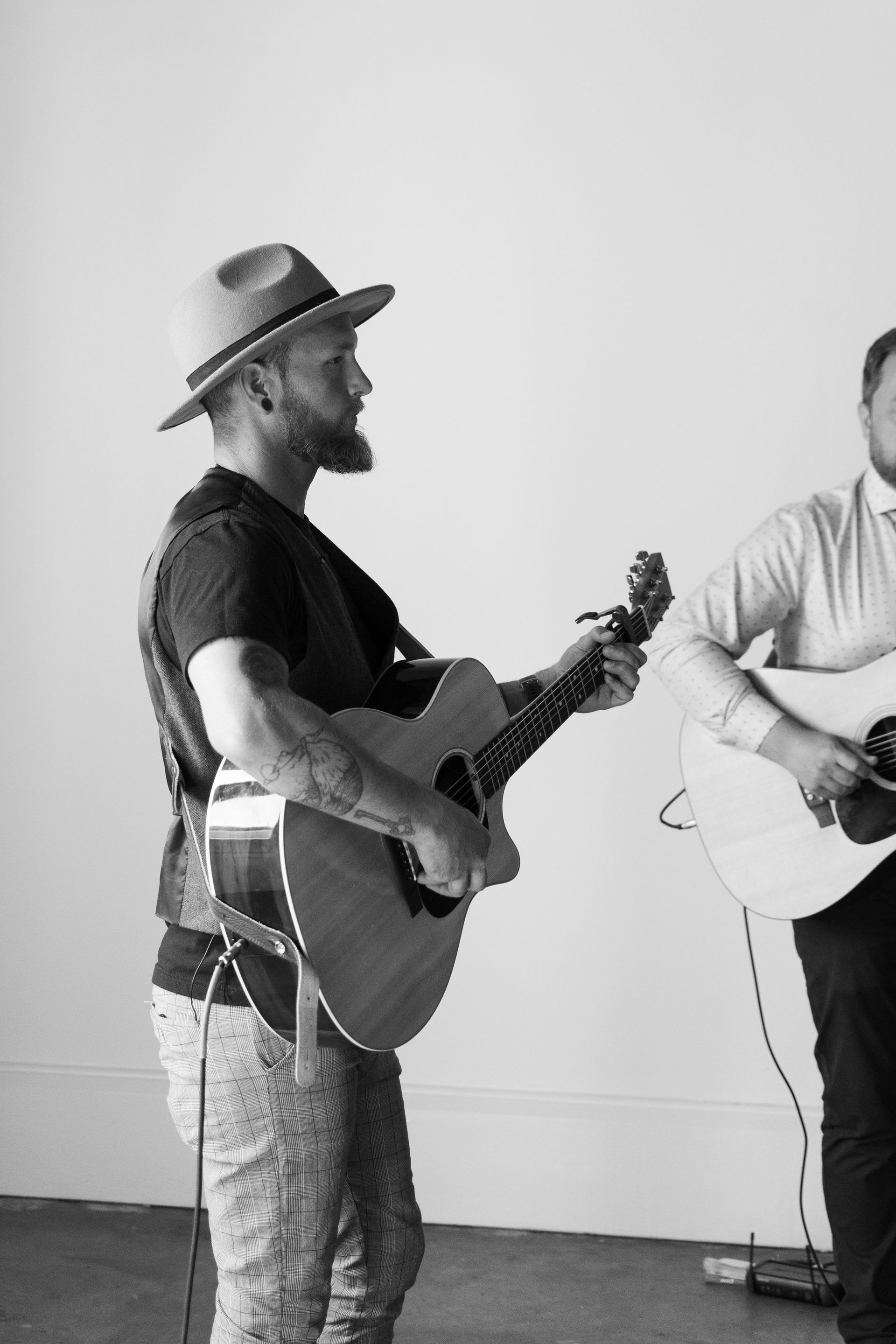 Two men are playing guitars in a black and white photo.