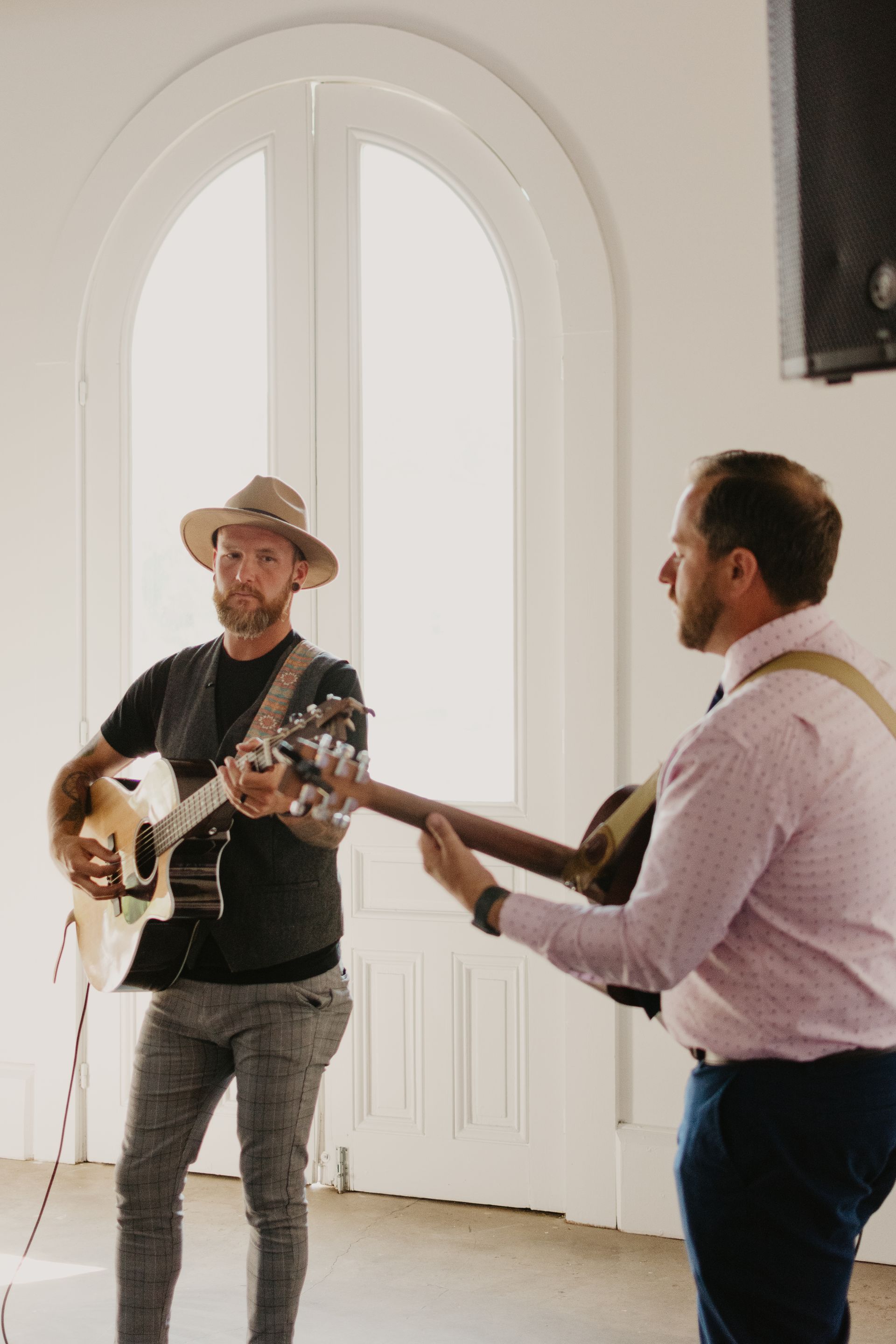 Two men are playing guitars in a room.