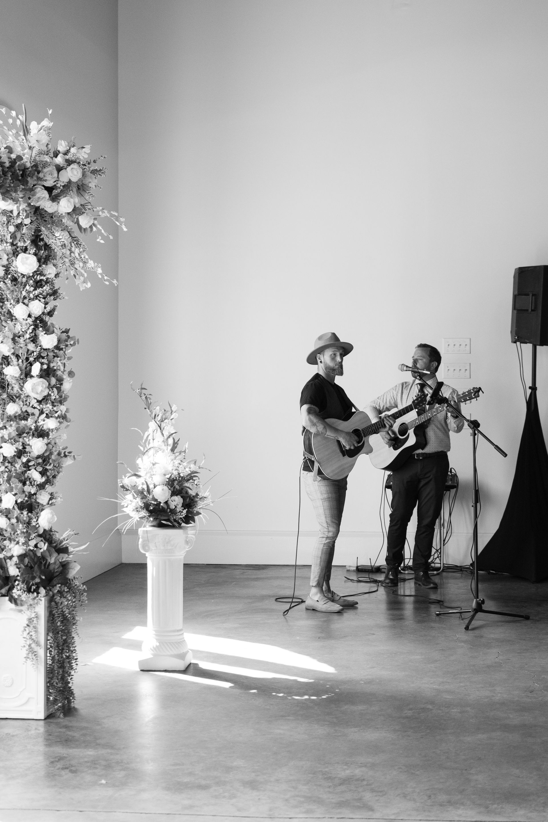 A black and white photo of two men playing guitars in a room.
