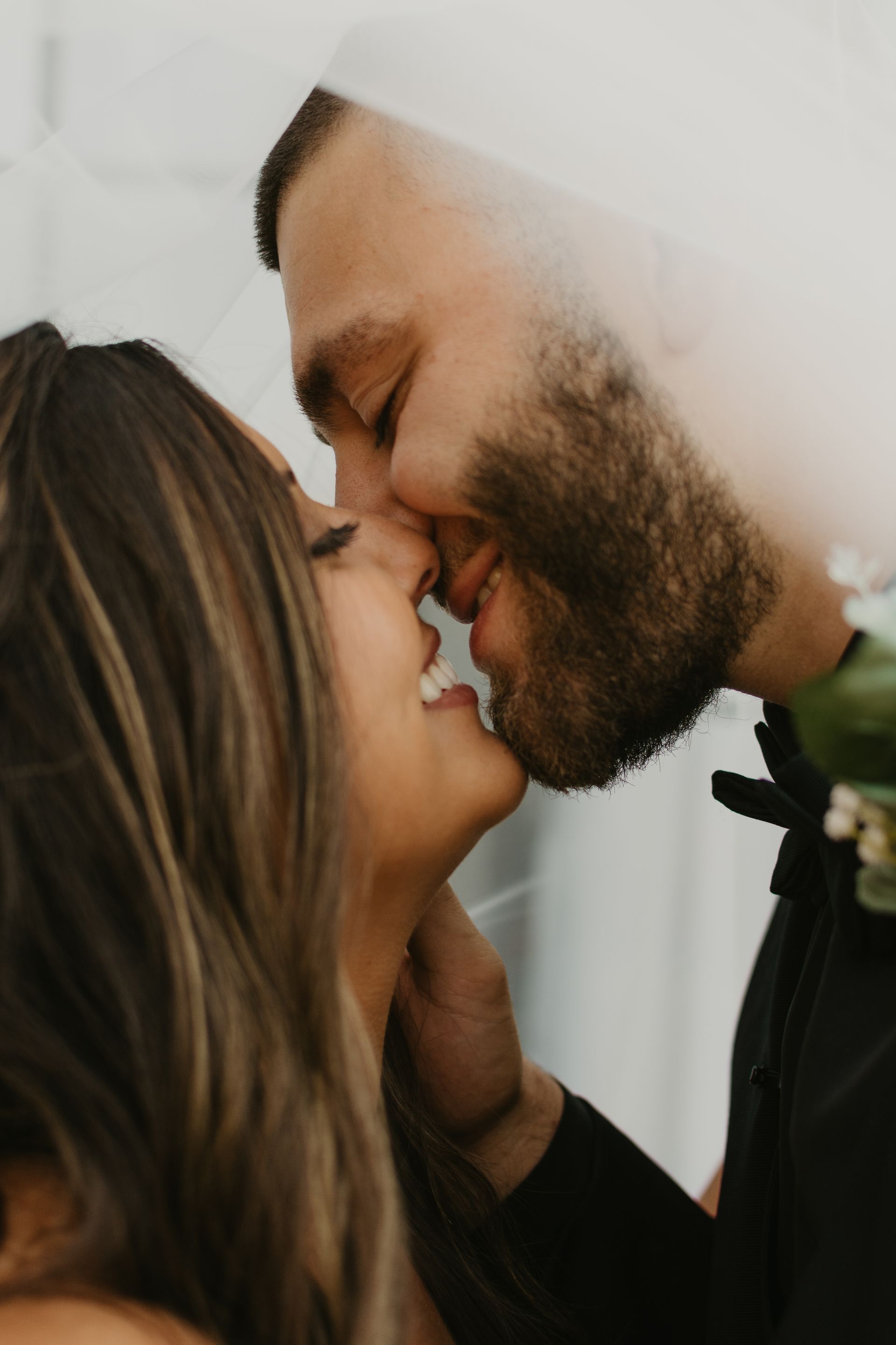 A man and a woman are kissing behind a veil.