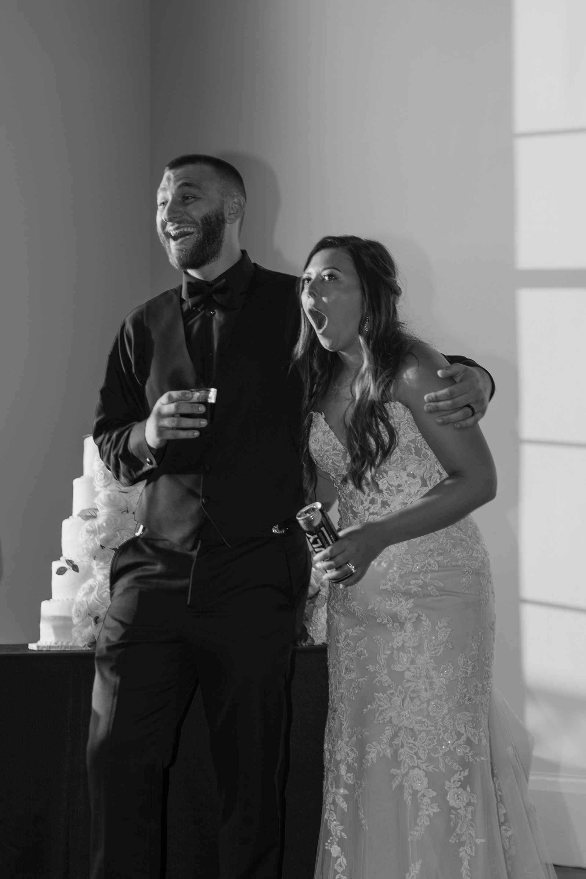 A bride and groom are standing next to each other in front of a wedding cake.