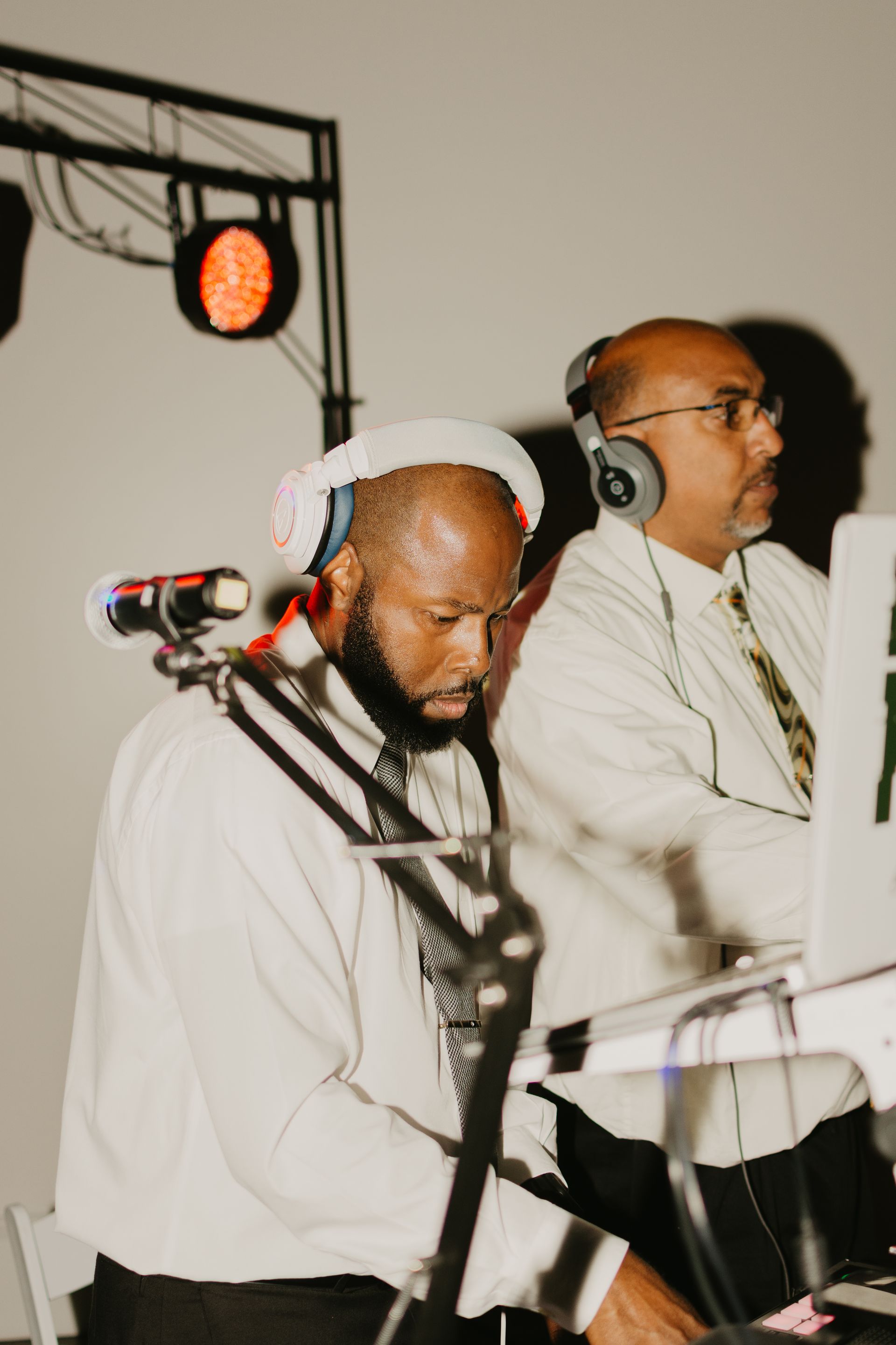 Two men wearing headphones are playing music at a party