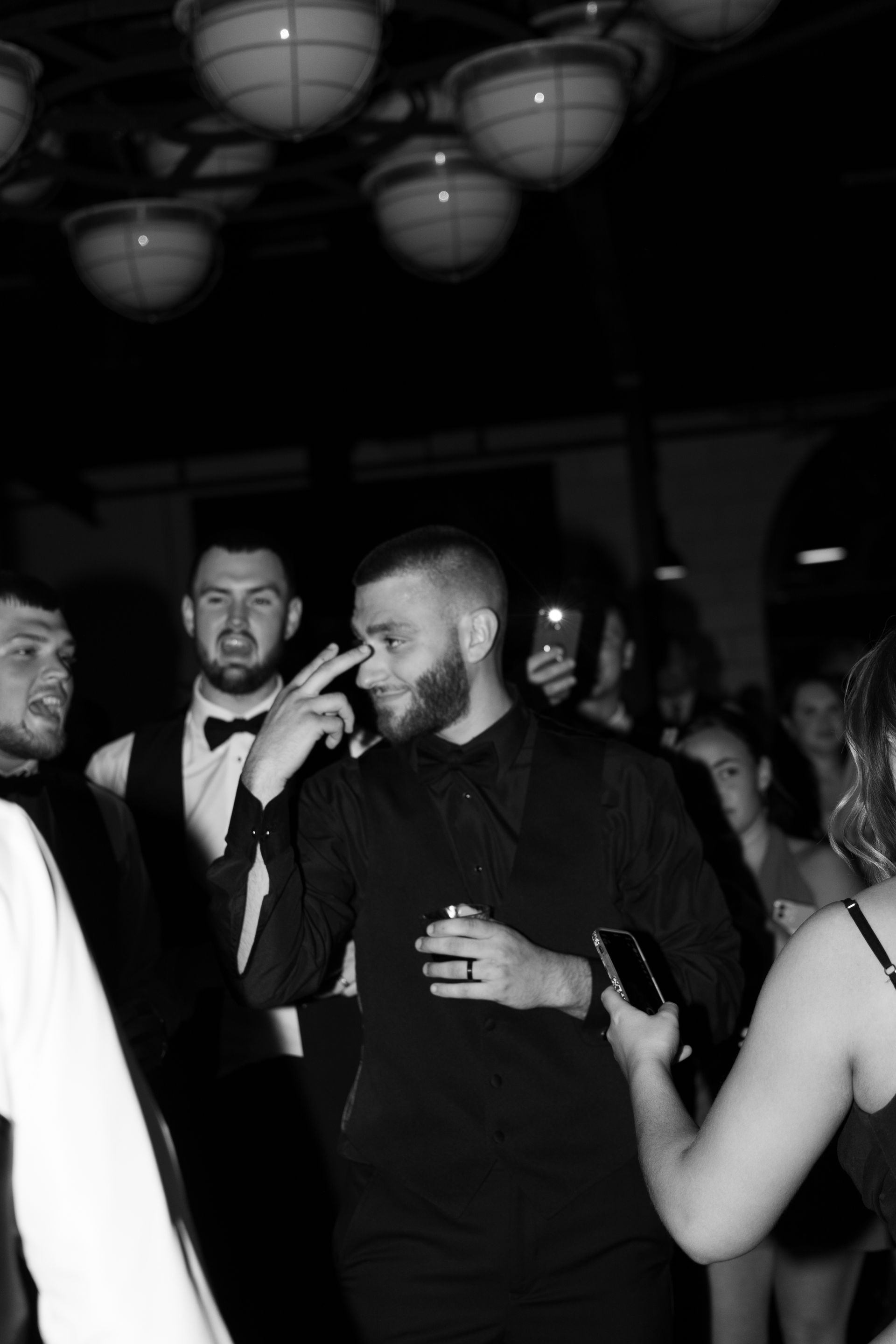 A black and white photo of a group of people dancing at a party.