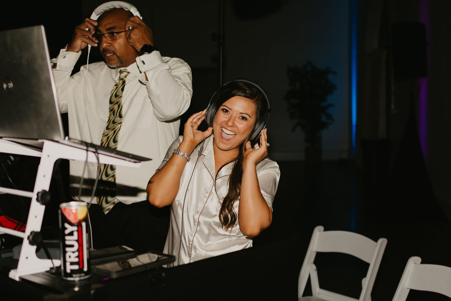 A man and a woman are playing music on a laptop.