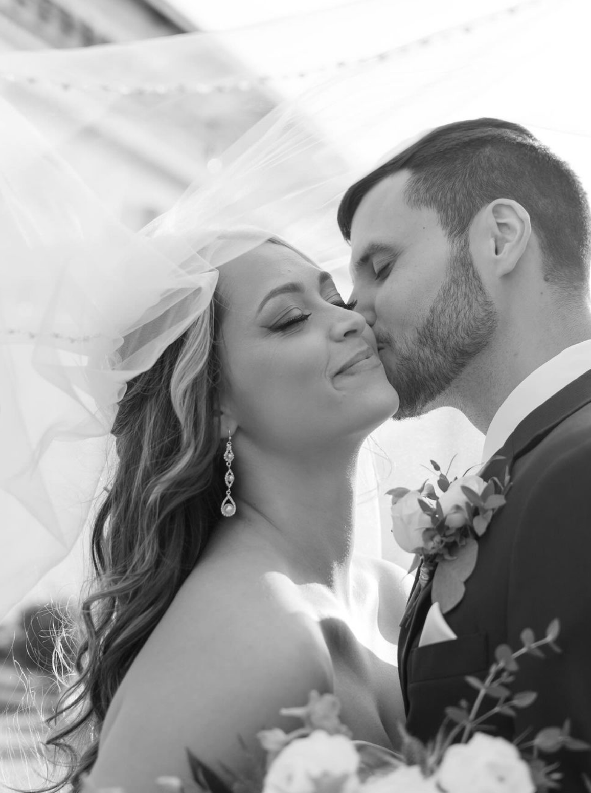 A bride and groom are kissing in a black and white photo.