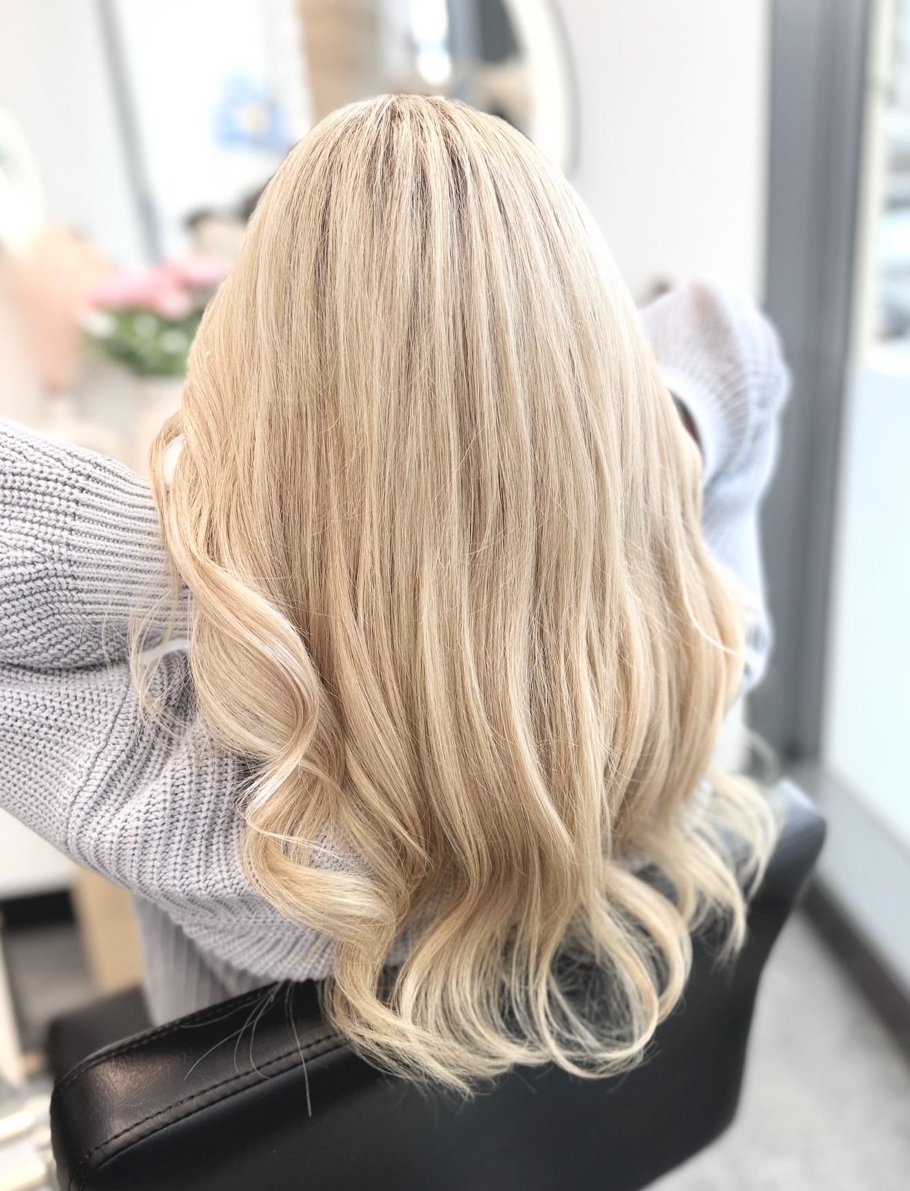 Blonde hair styled in thin braids, with loose waves, viewed from the back.