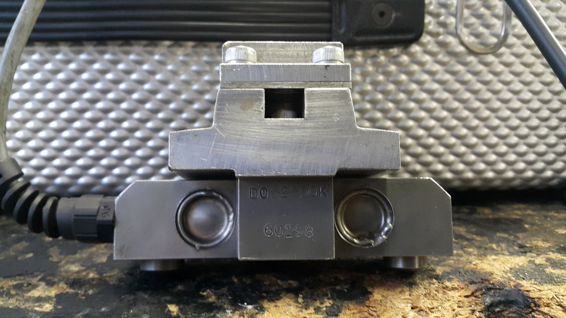 A metal object is sitting on a table next to a laptop.