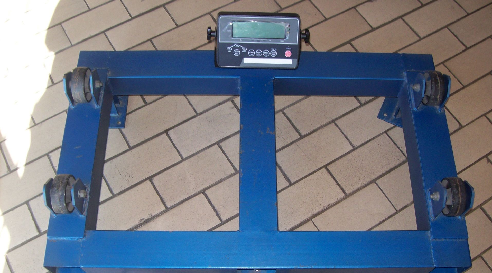 A blue scale is sitting on a brick floor