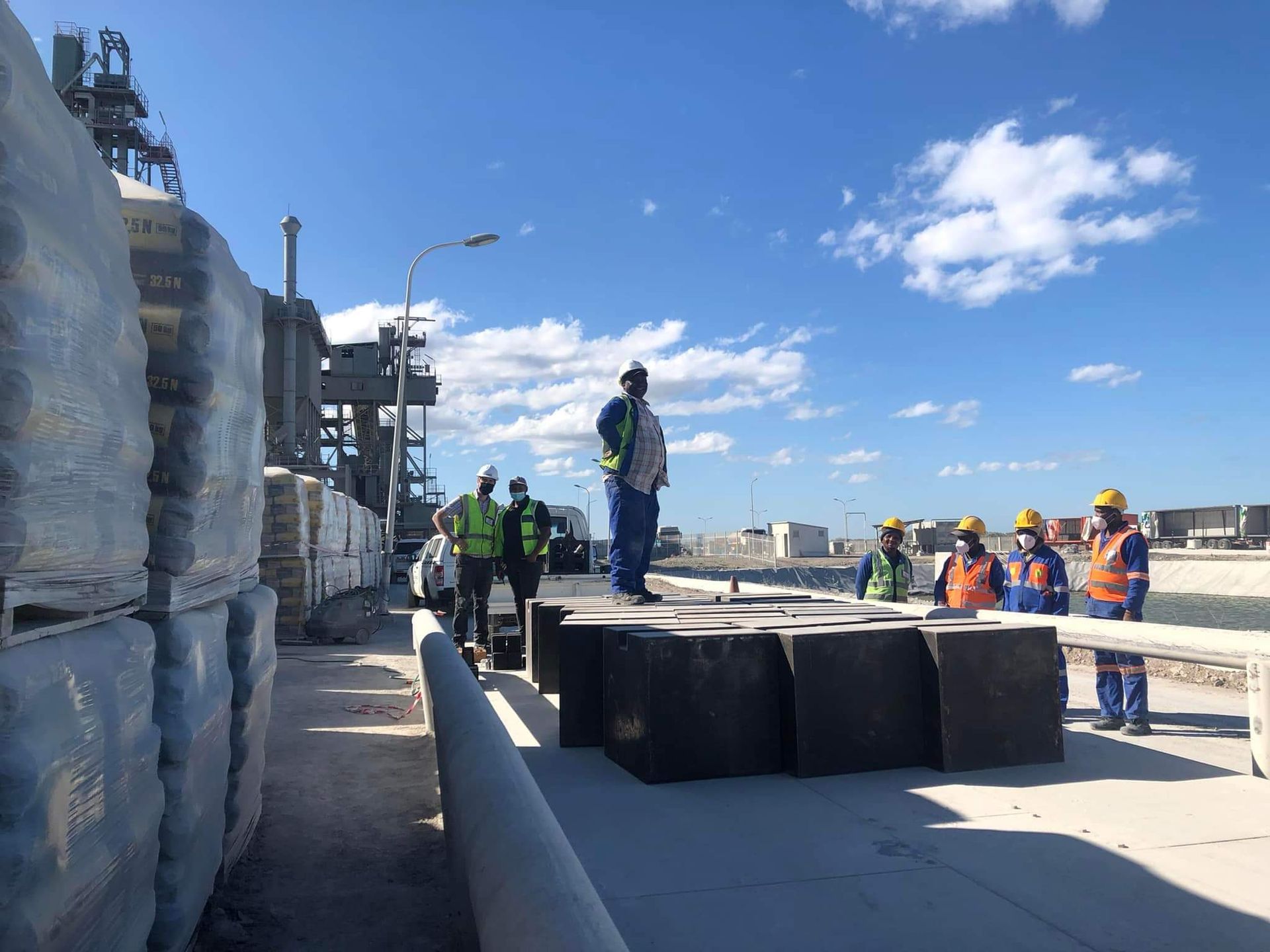 A group of construction workers are standing on top of a bridge.
