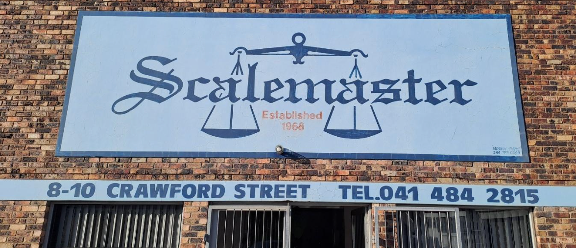 A scalemaster sign is on the side of a brick building.