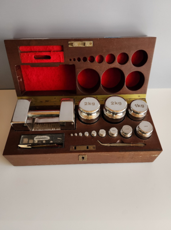 A wooden box filled with silver weights and a red velvet lining