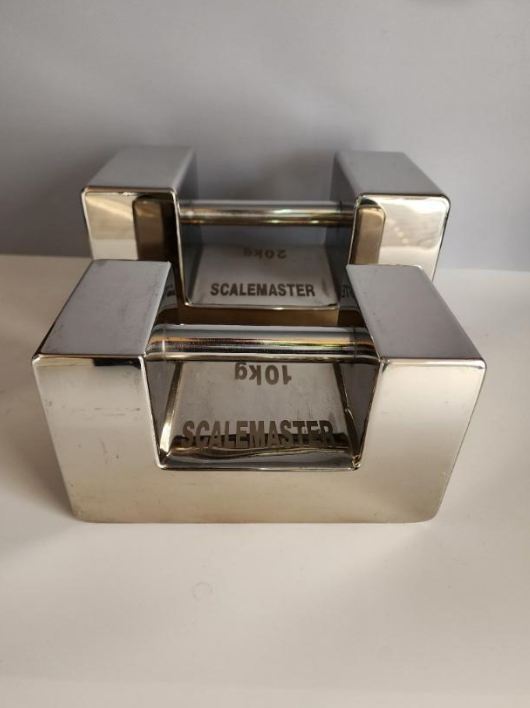 A stainless steel scale is sitting on top of a white table.