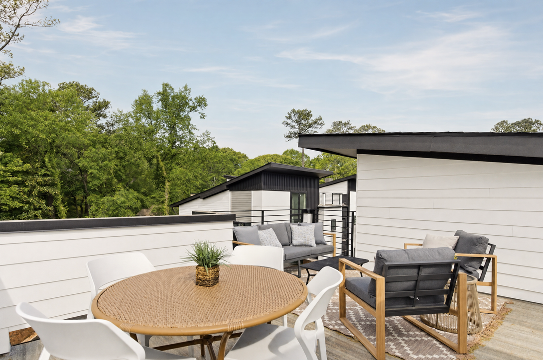 Outdoor patio with round table, white chairs, and lounge seating on a rooftop deck.