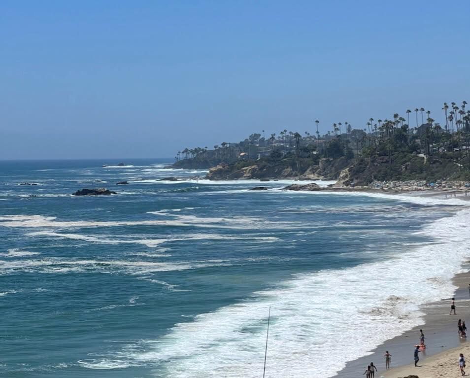A group of people are walking on a beach near the ocean