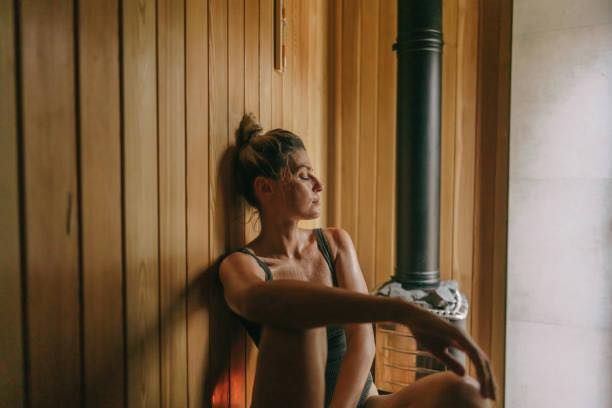 A woman in lingerie is sitting in a wooden sauna.