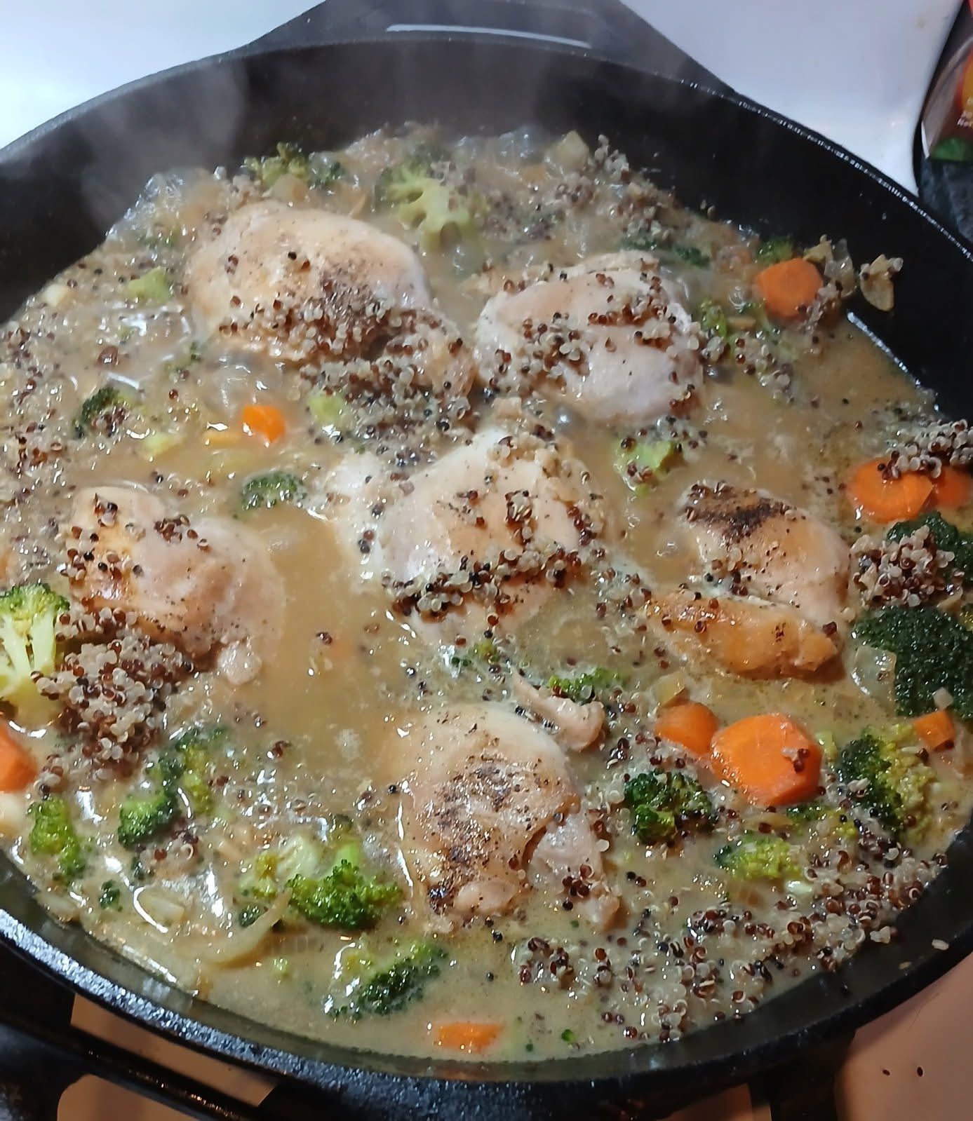 Chicken broccoli and carrots are being cooked in a skillet