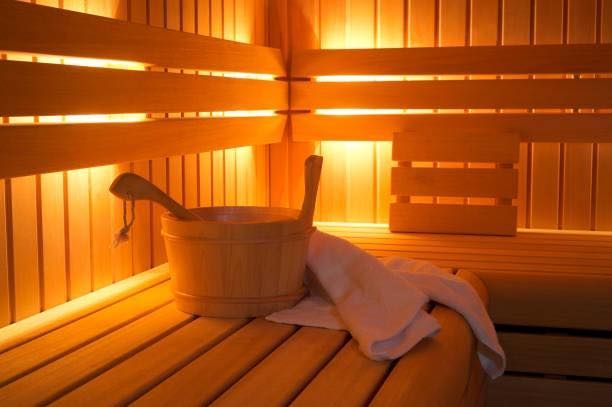 A wooden sauna with a bucket and a towel on the bench