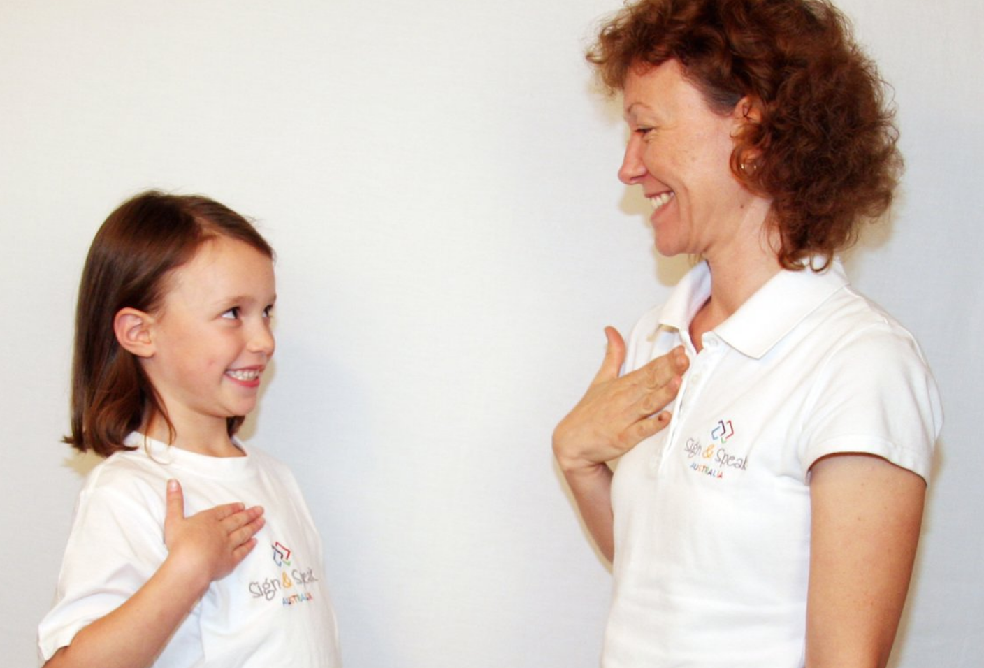 A woman and a little girl are standing next to each other and smiling.