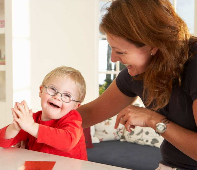 A woman is playing with a little boy who is wearing glasses