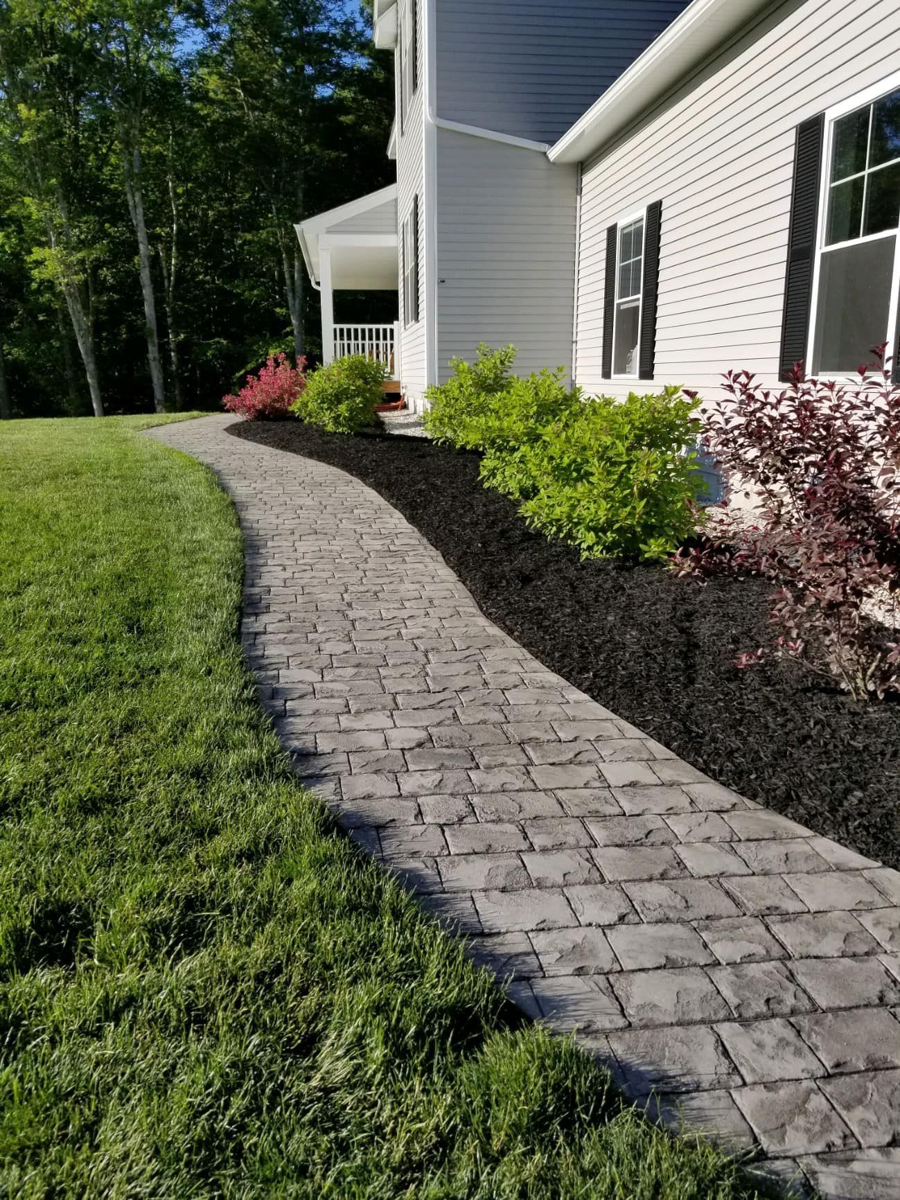A walkway leading to a house with a lush green lawn.