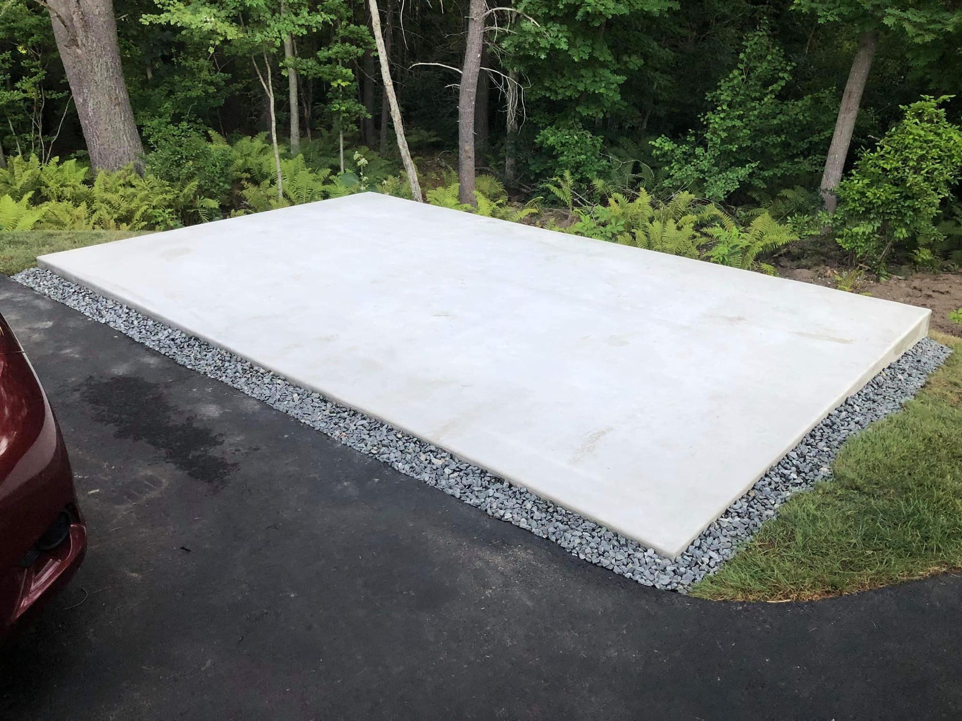 A car is parked on the side of a road next to a large concrete slab.