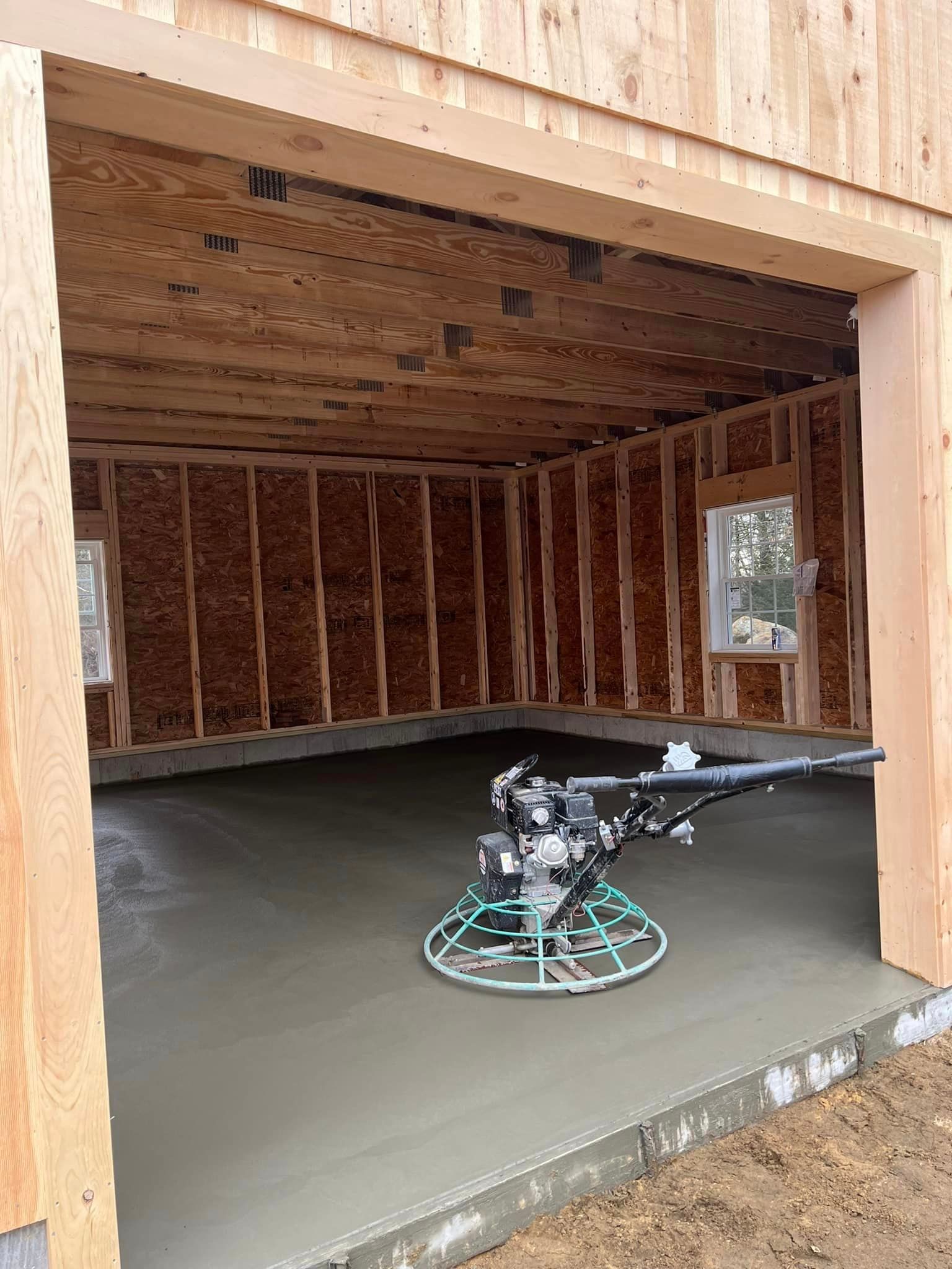 A concrete trowel is sitting in a garage under construction.