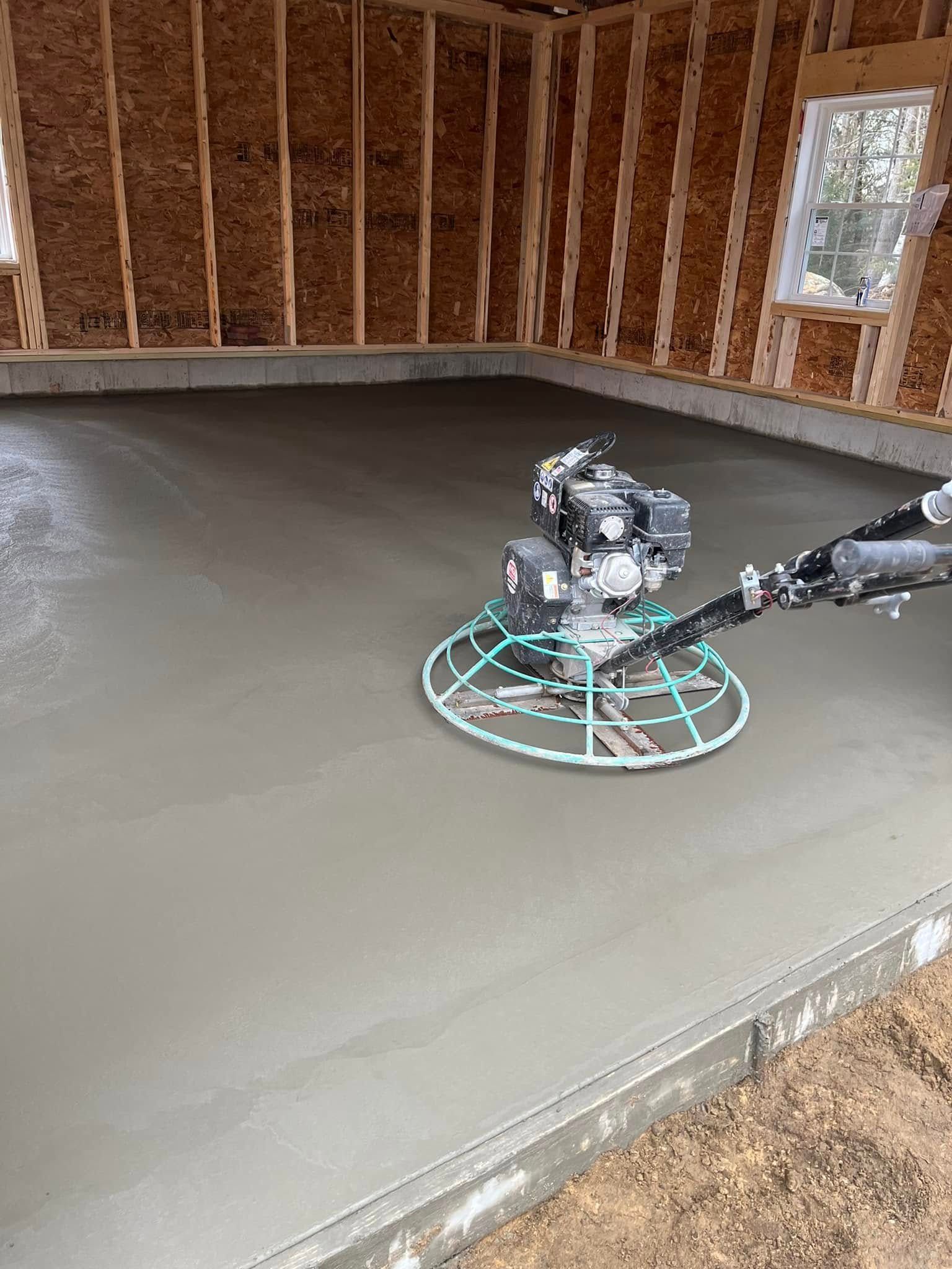 A person is using a trowel on a concrete floor.